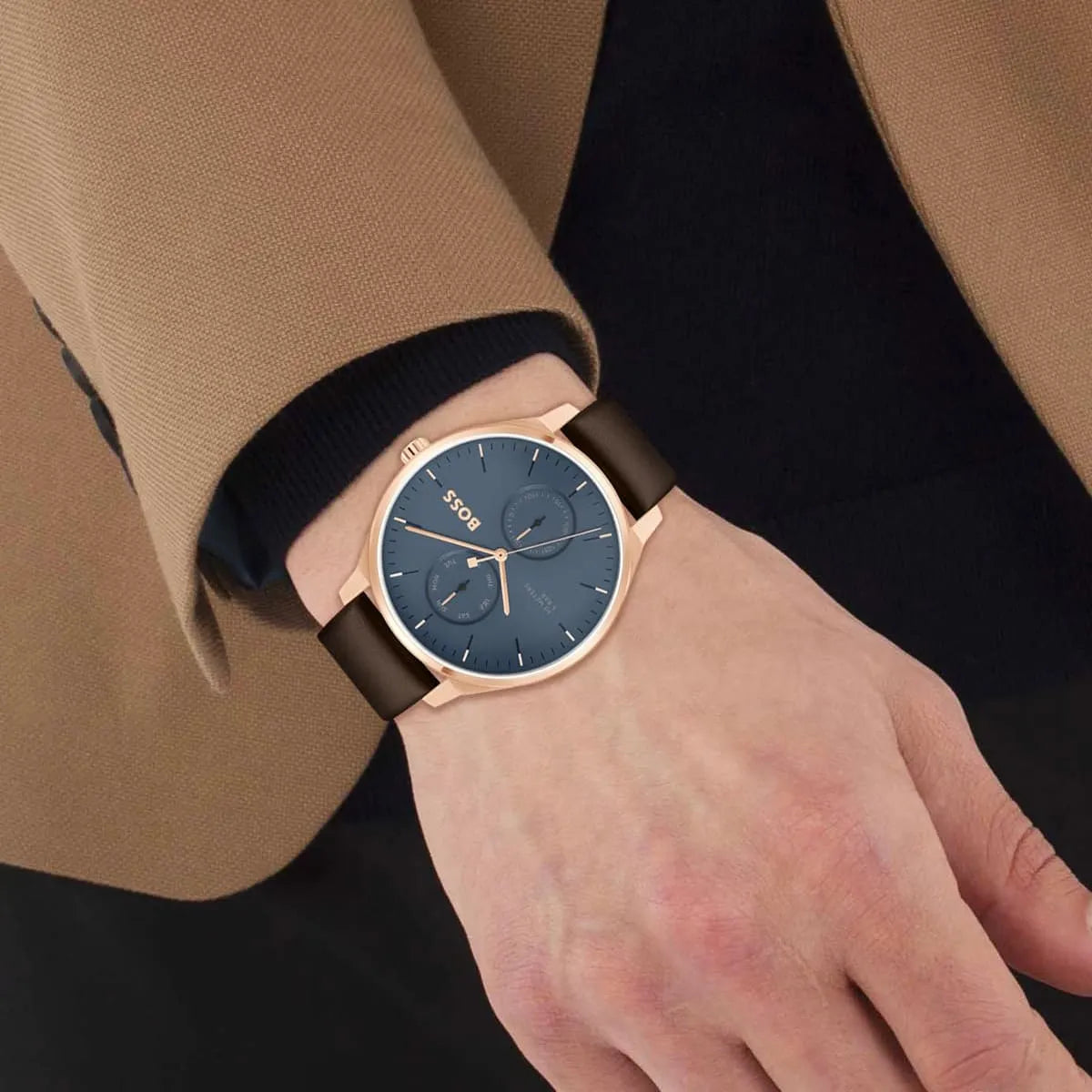 Hugo Boss Tyler watch worn on wrist with business attire, rose gold case and blue dial