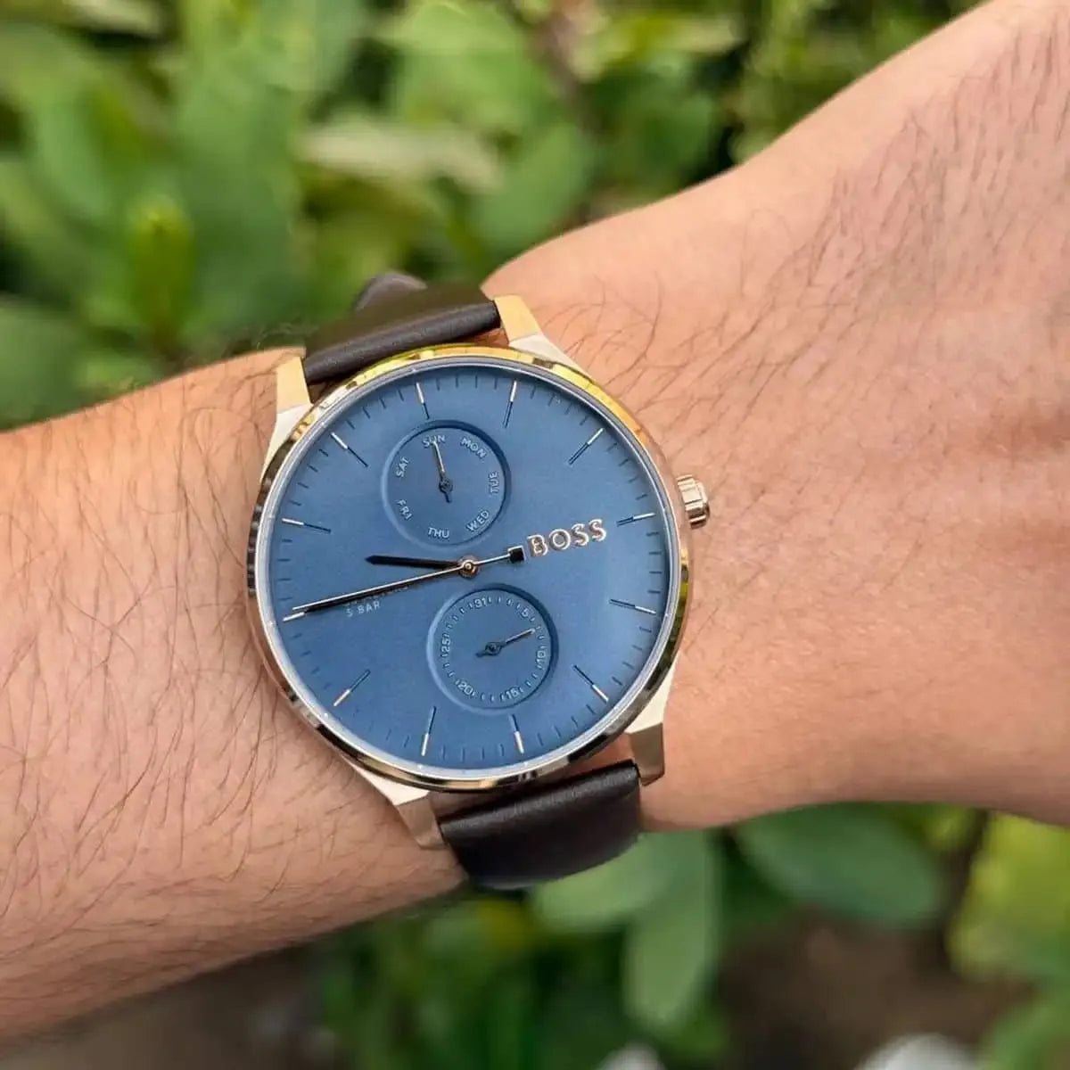 Hugo Boss Tyler watch worn on wrist outdoors, blue dial with subdials and rose gold case