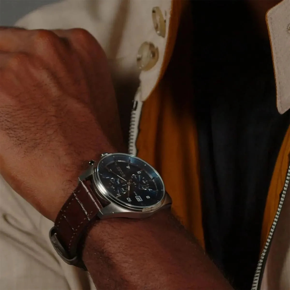 Men wearing Hugo Boss Skytraveller watch on wrist with blue chronograph dial and brown leather band