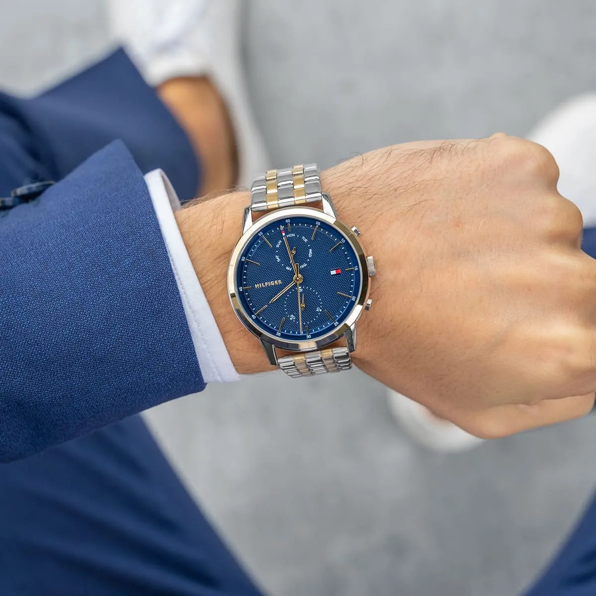 Two-tone steel and gold men's watch on wrist showing navy dial with chronograph subdials