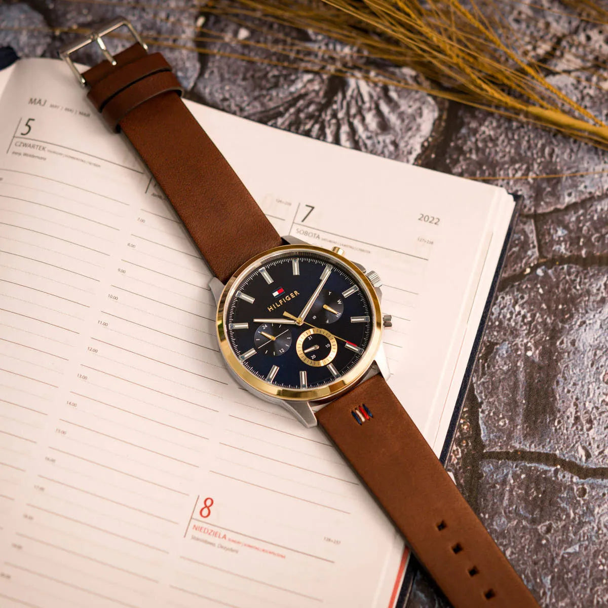 Tommy Hilfiger Ryder watch worn on wrist with planner and flowers