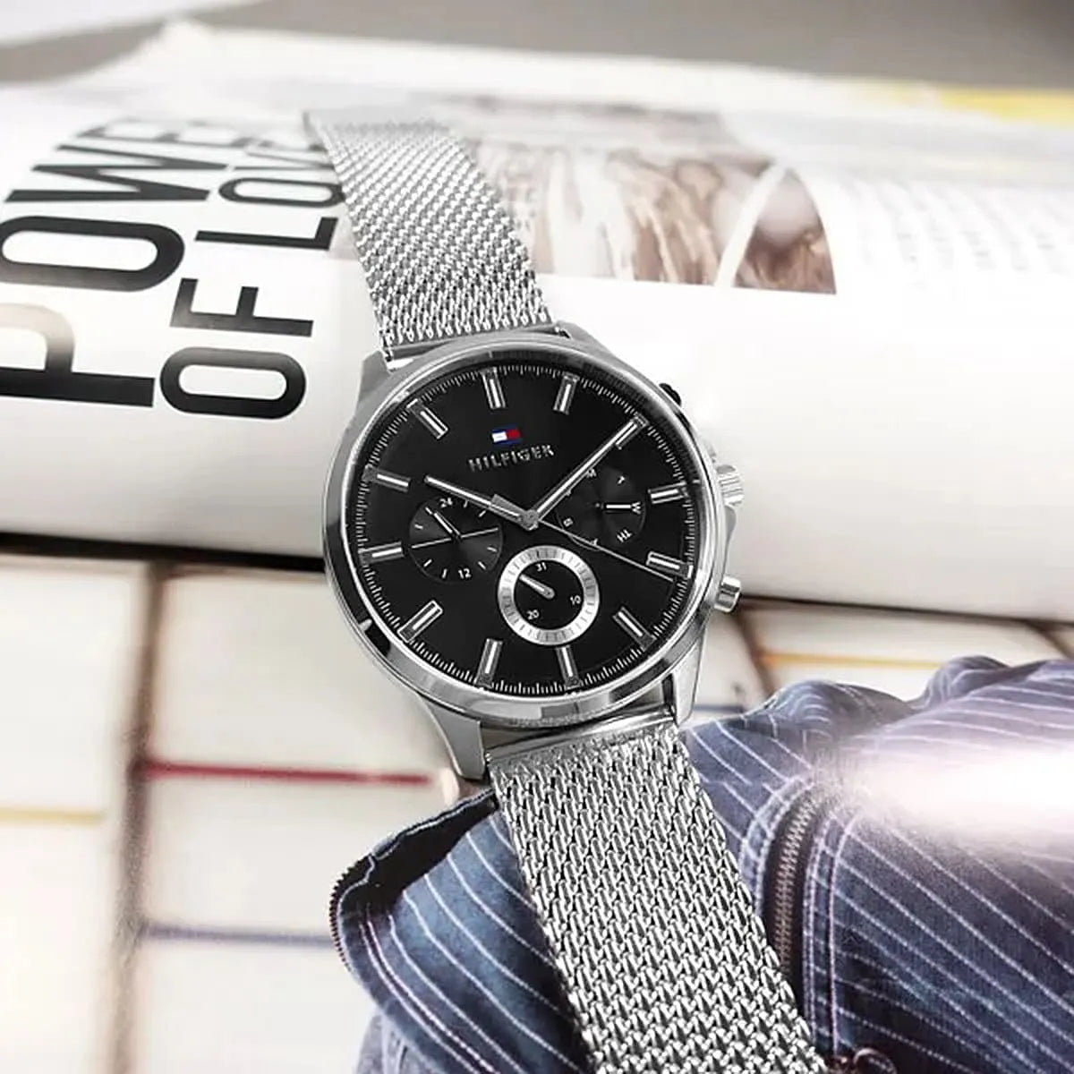 Tommy Hilfiger Ryder watch with black dial displayed on magazine
