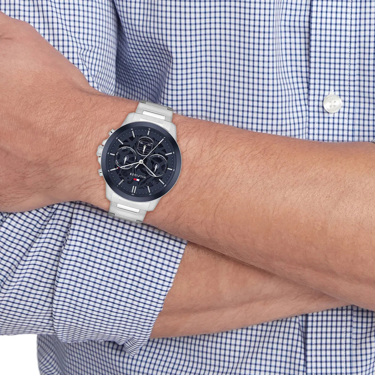 Tommy Hilfiger Henry watch on wrist with checked shirt cuff showing navy dial and metal bracelet