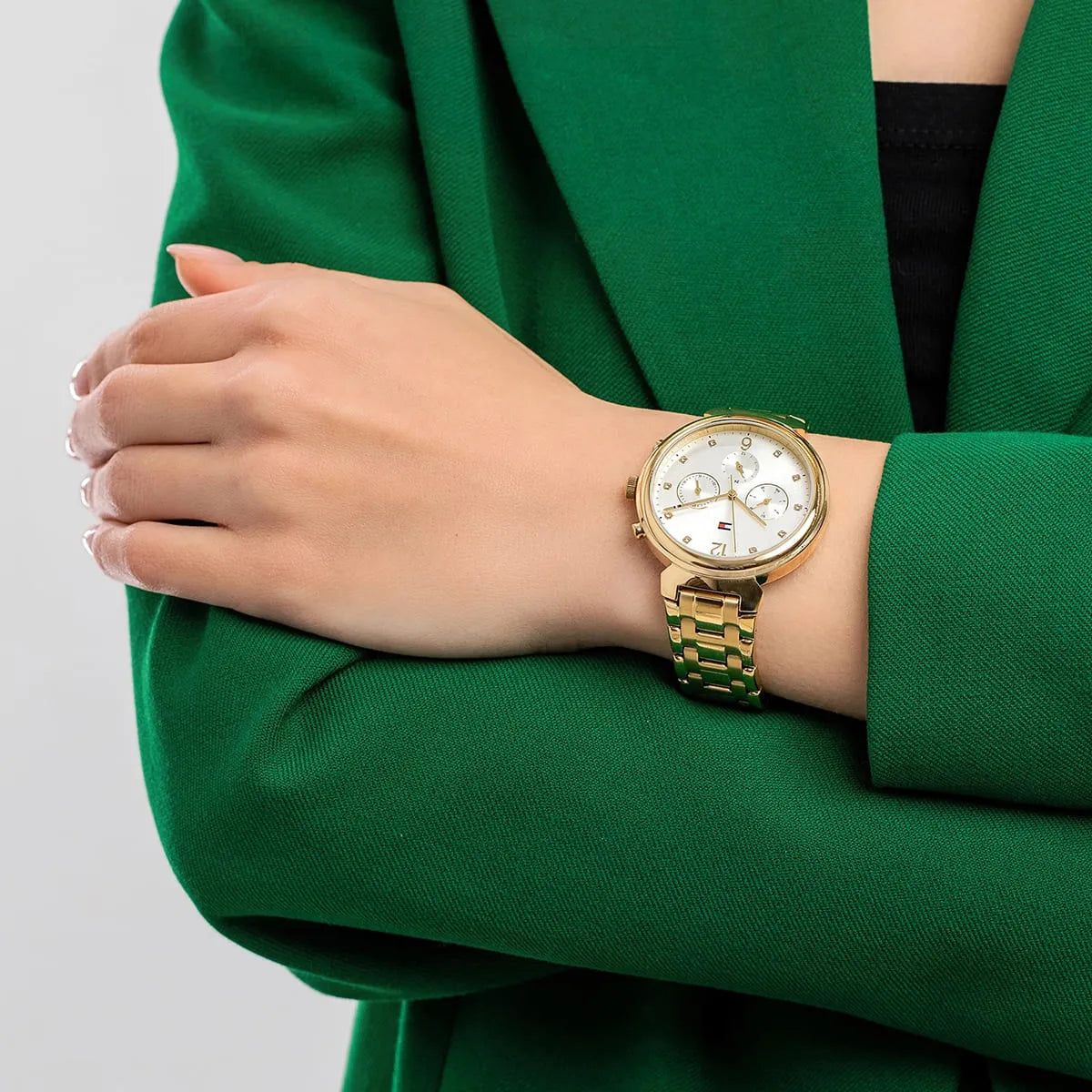 Tommy Hilfiger Ivy gold stainless steel watch worn on woman's wrist with green jacket
