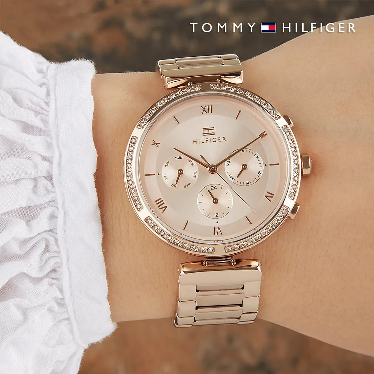 Tommy Hilfiger rose gold watch on wrist with chronograph dial and crystal-set bezel detail
