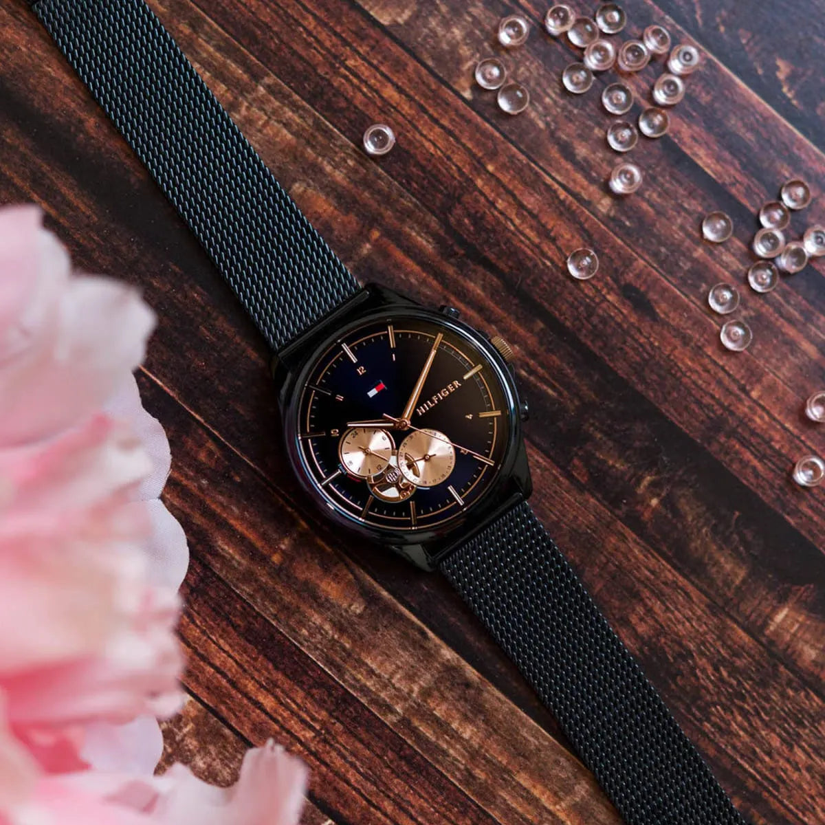 Tommy Hilfiger women's watch displayed on wooden surface with flowers