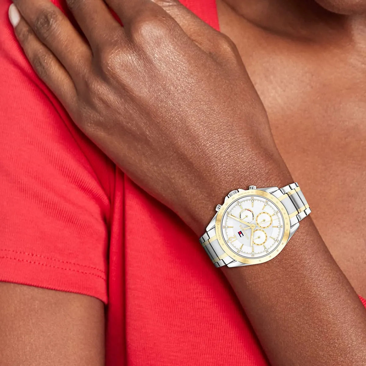 Two-tone women's watch on wrist wearing bright pink sleeve