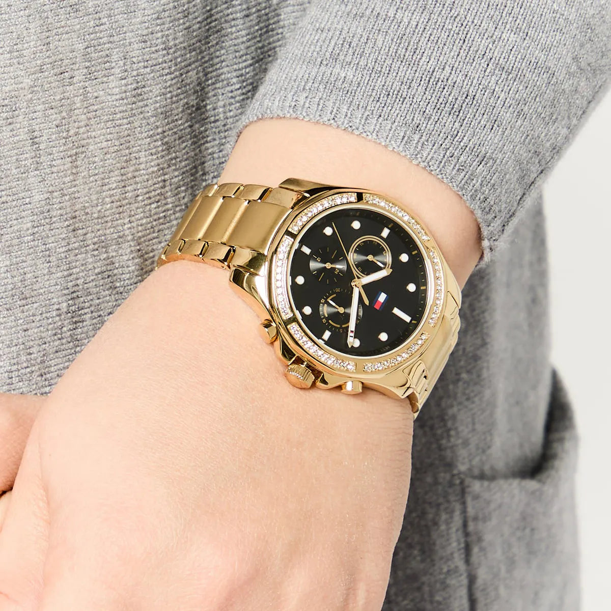 Tommy Hilfiger Libby women's watch worn on wrist with gray sleeve and gold bracelet