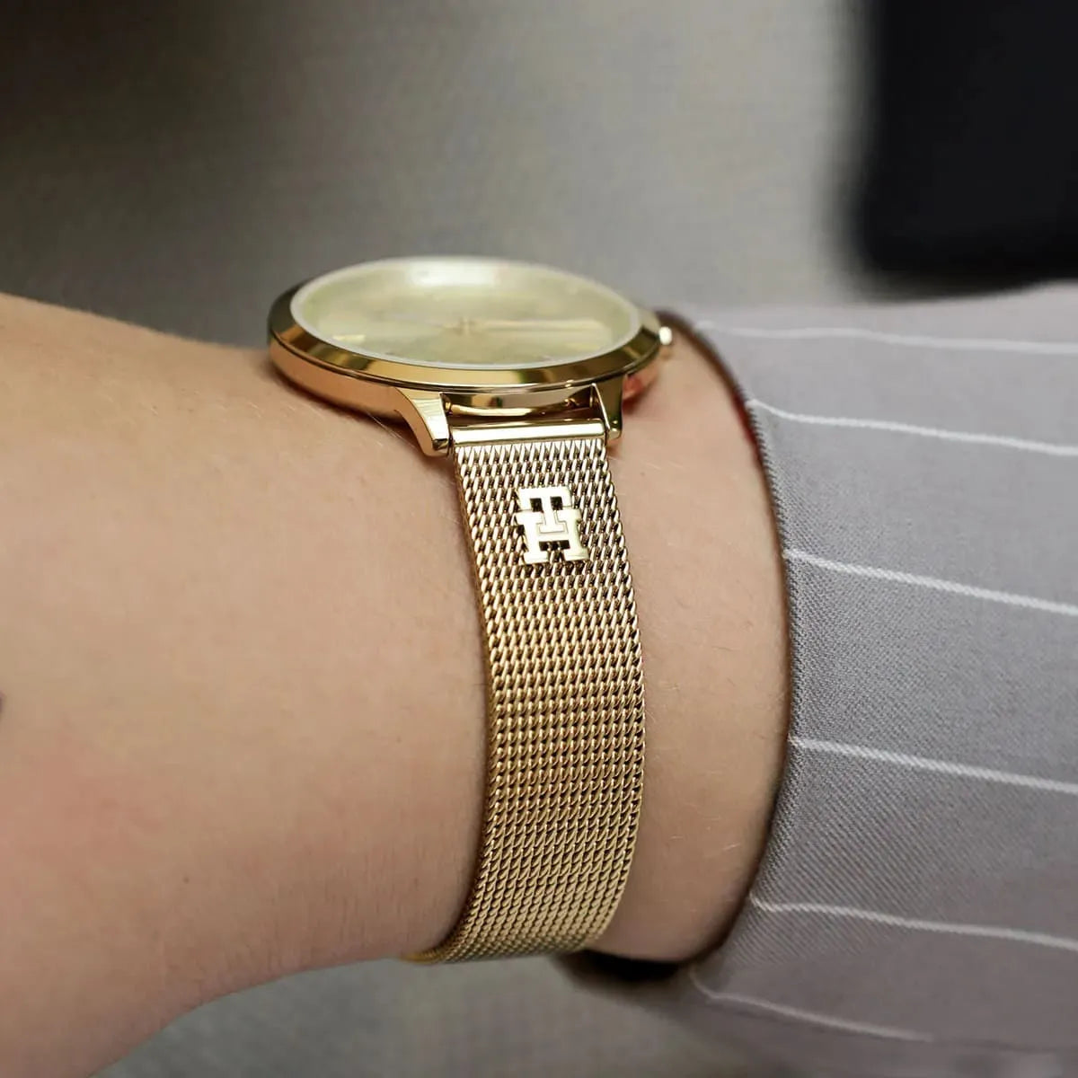 Gold-tone Tommy Hilfiger watch with light champagne dial worn on wrist