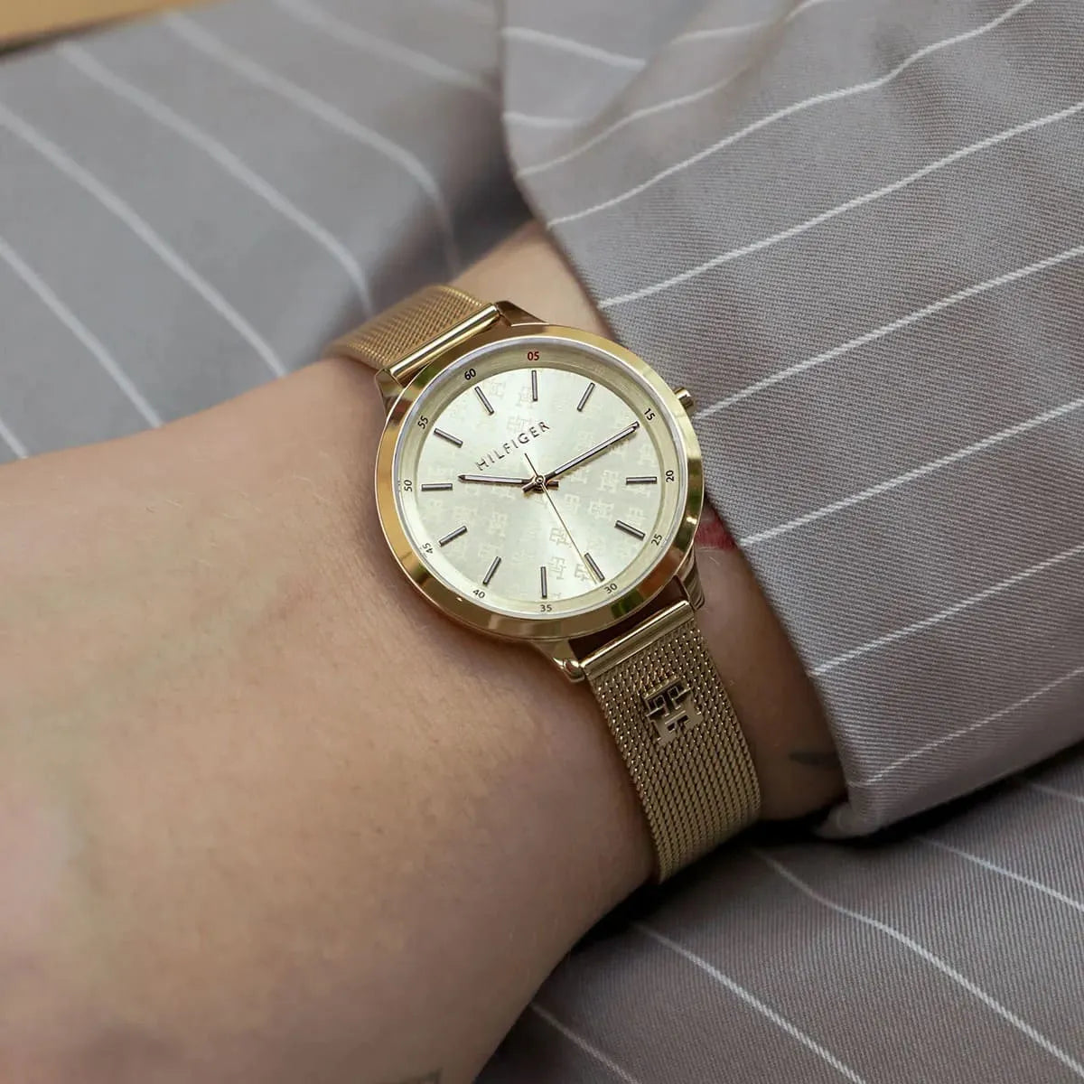 Gold Tommy Hilfiger women's slim watch worn on wrist with light champagne dial