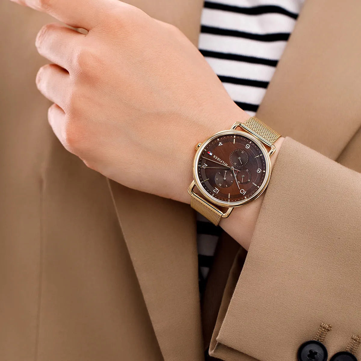 Tommy Hilfiger Lily watch worn on wrist with brown dial and gold mesh strap