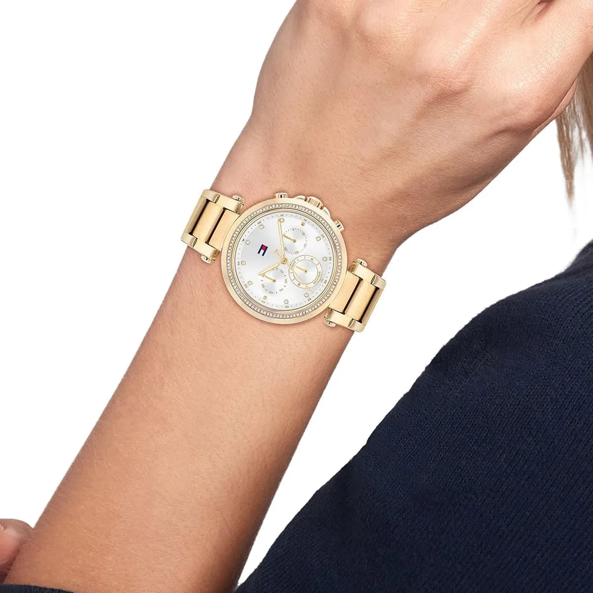 Tommy Hilfiger Emily women's watch worn on wrist with gold link bracelet and silver chronograph dial