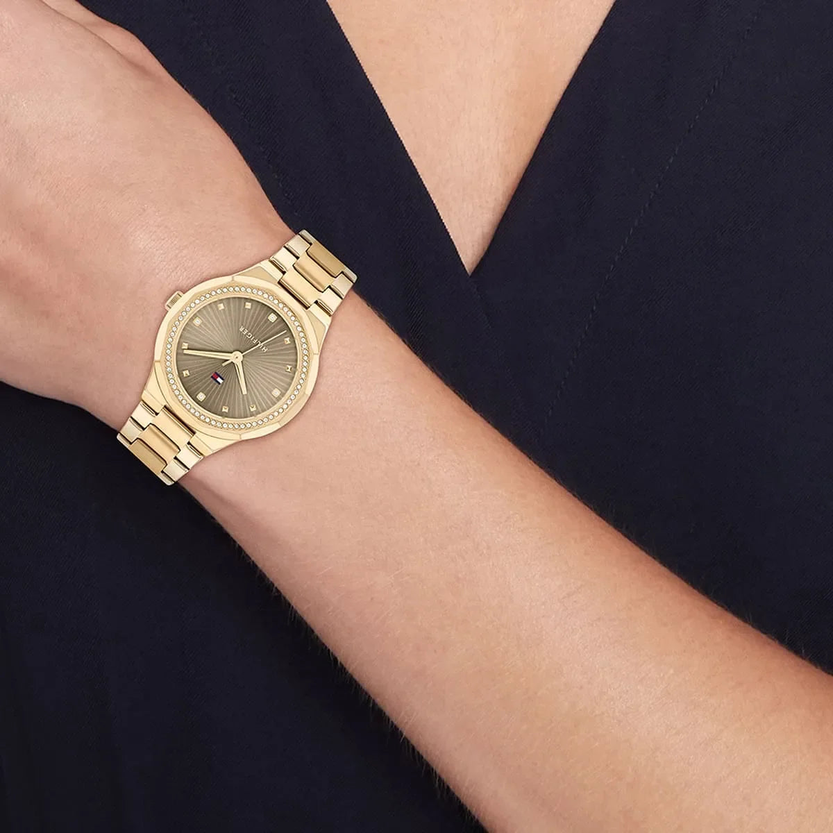 Tommy Hilfiger gold watch worn on wrist with crystal bezel and brown dial
