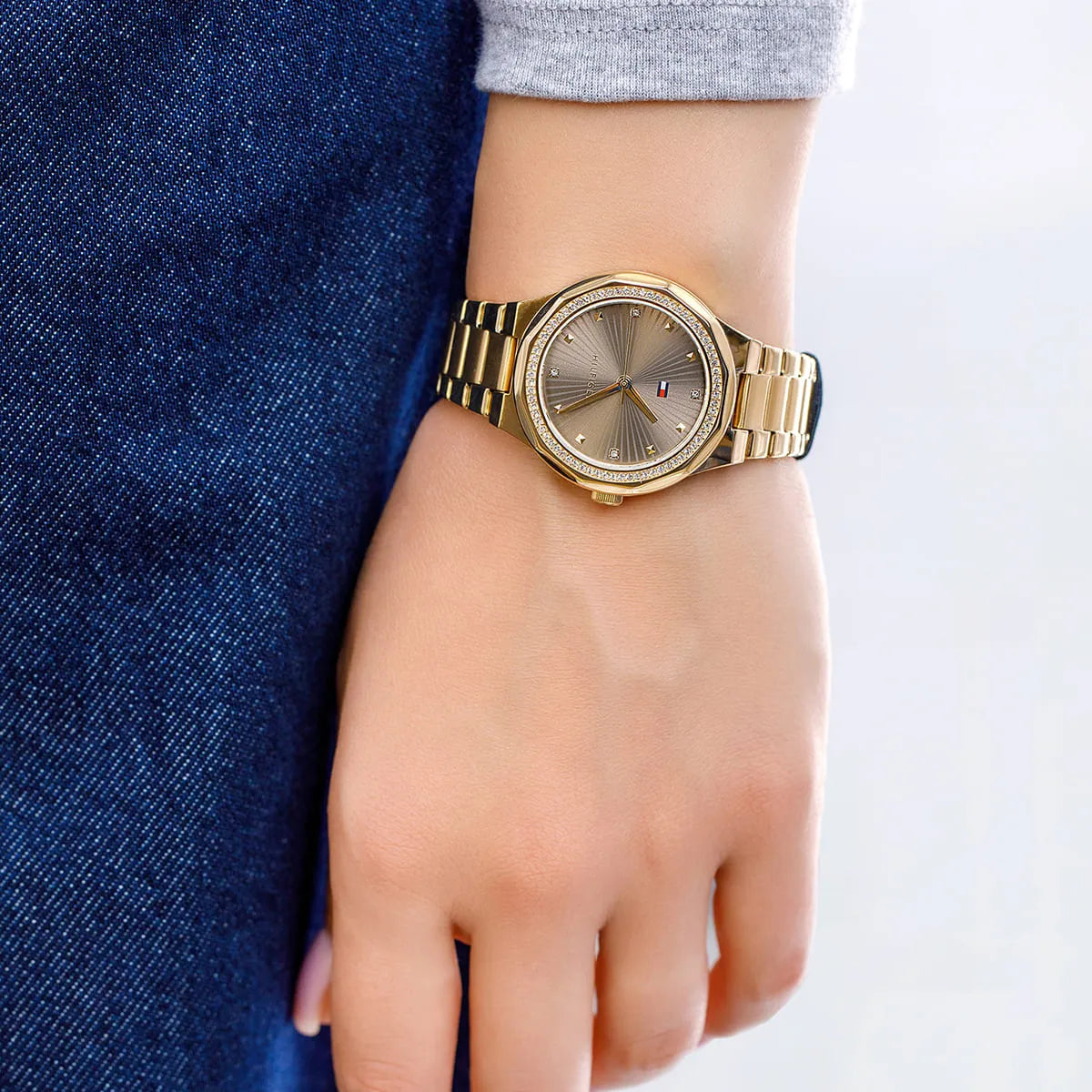 Tommy Hilfiger gold watch worn on wrist with brown dial and crystal bezel