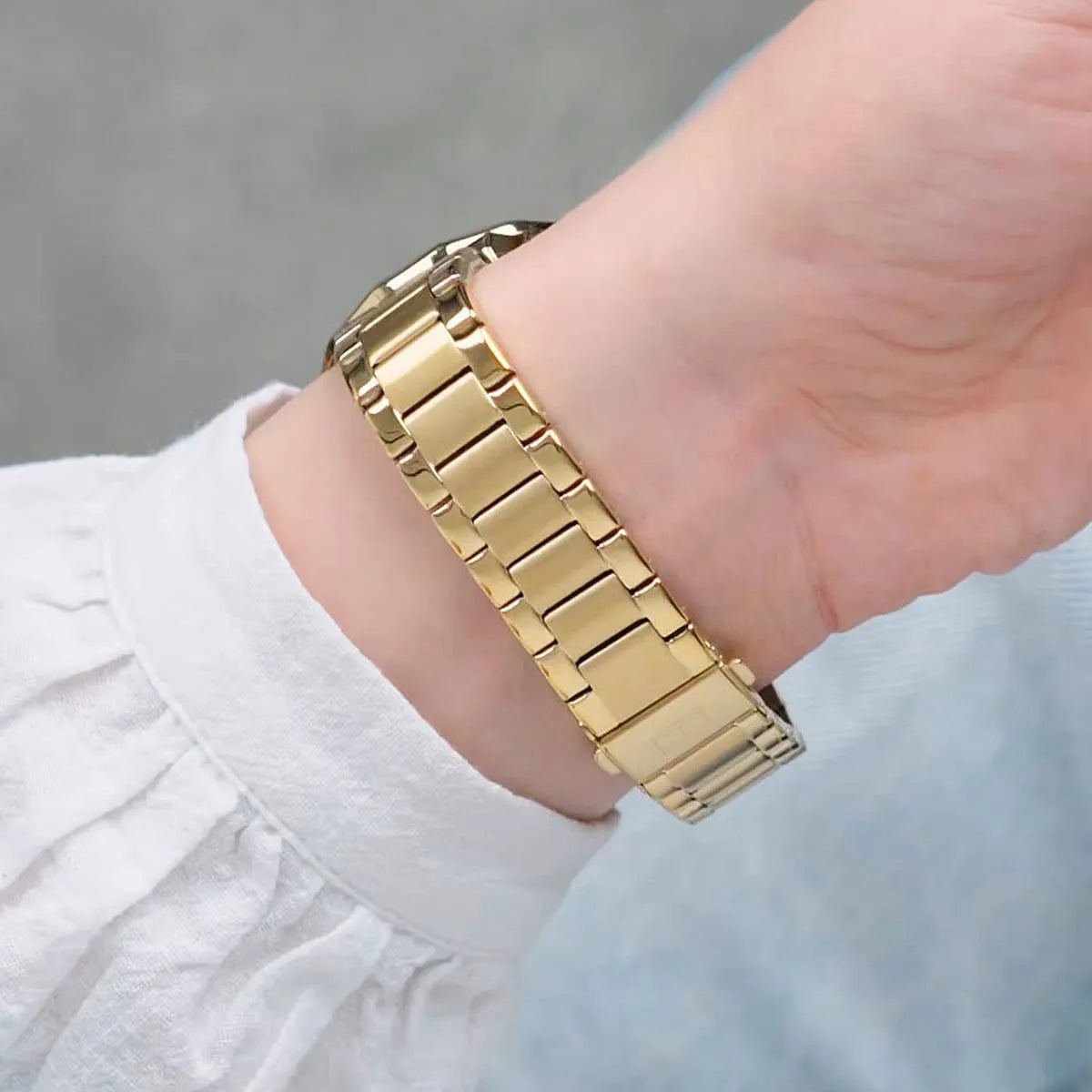 Gold metal bracelet of Tommy Hilfiger watch shown on wrist