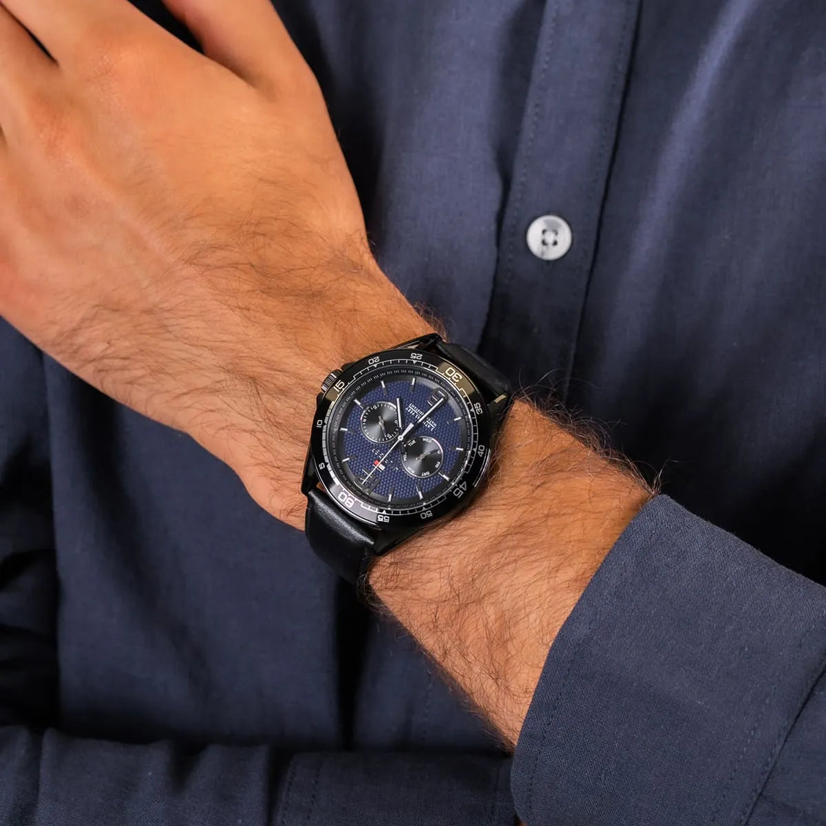 Tommy Hilfiger 46mm chronograph watch on wrist with blue dial and black leather band
