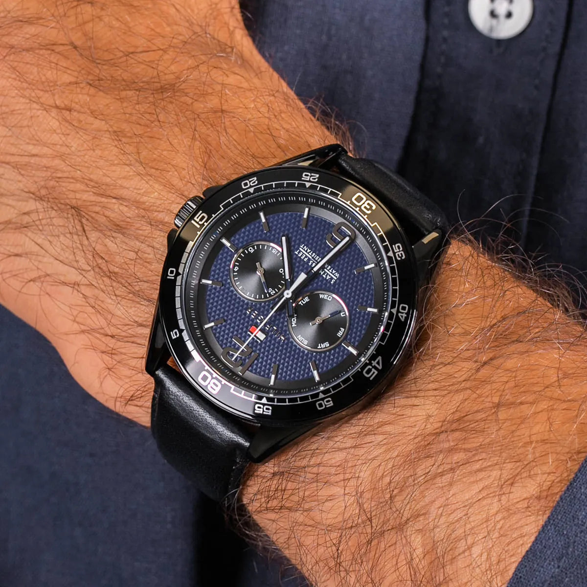 Tommy Hilfiger men's watch worn on wrist showing blue dial and black leather strap