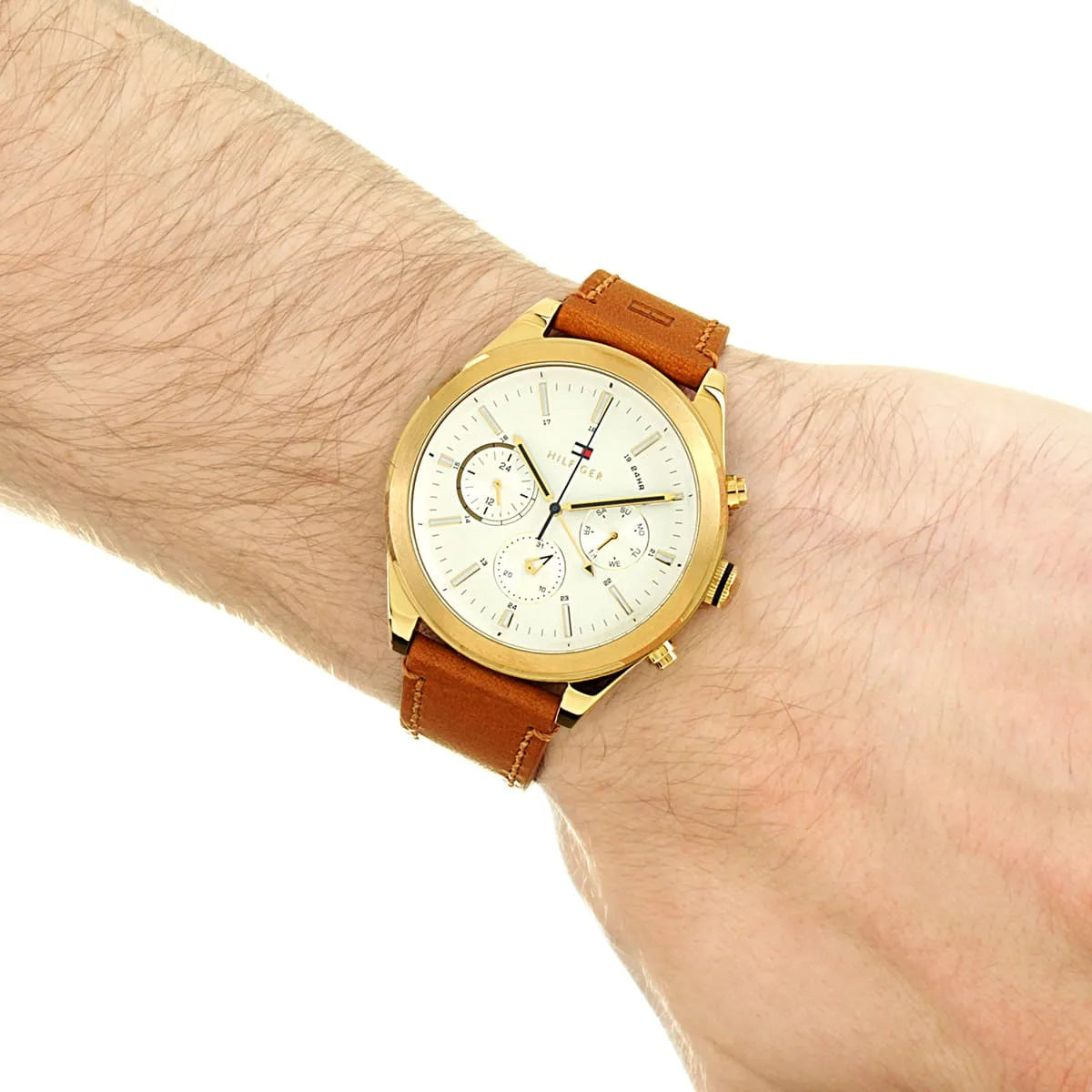 Tommy Hilfiger watch worn on wrist showing gold case and brown leather strap styling