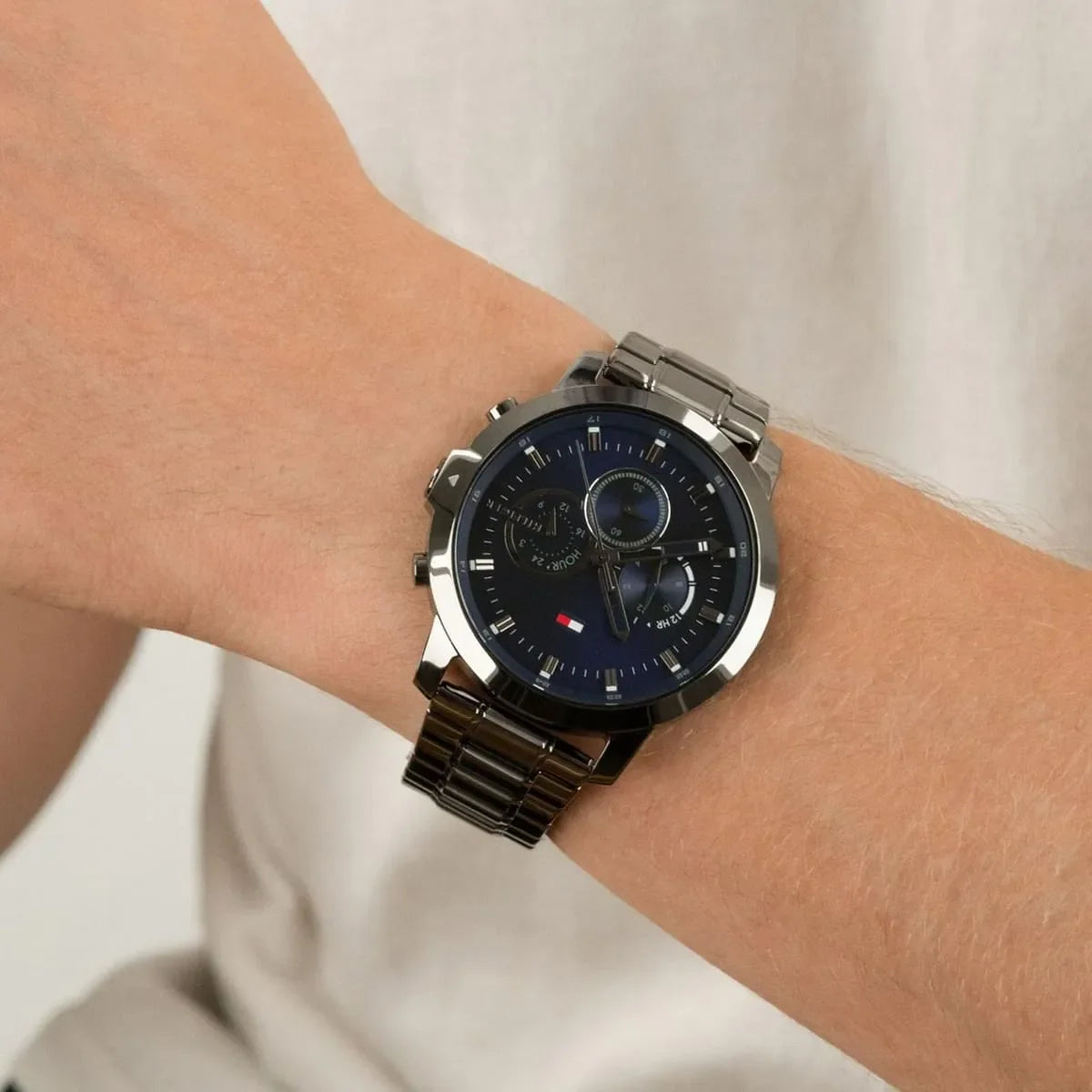 Tommy Hilfiger men's watch on wrist showing blue dial, chronograph subdials, and metal bracelet