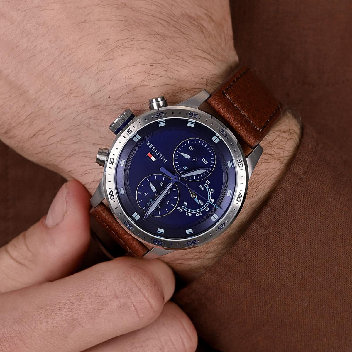 Tommy Hilfiger chronograph watch on wrist showing blue dial and brown leather strap