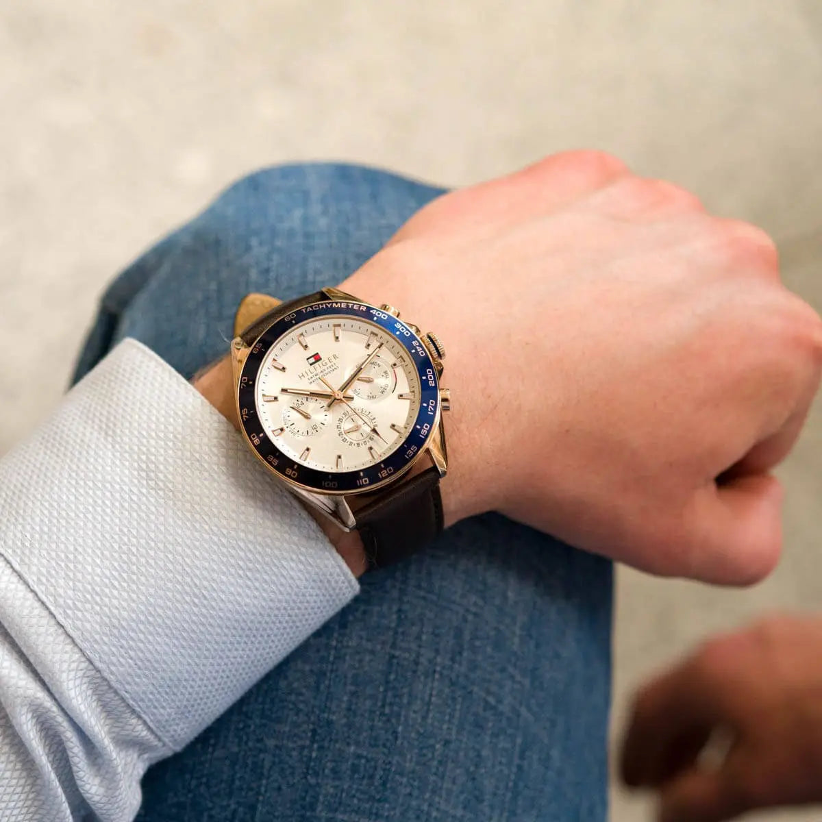 Tommy Hilfiger 1791966 chronograph watch worn on wrist with brown leather strap and white shirt