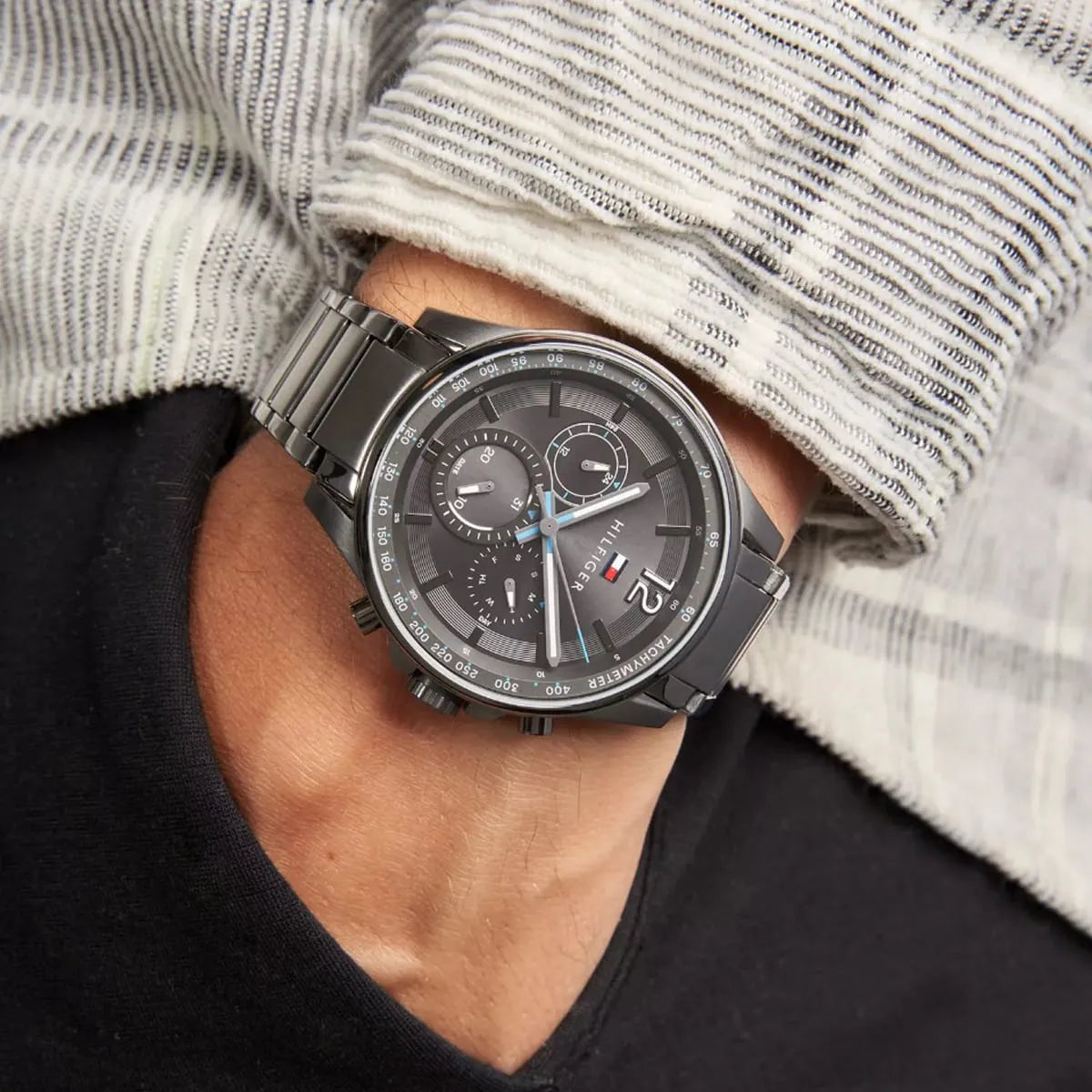 Tommy Hilfiger Max grey chronograph watch worn on wrist with striped shirt