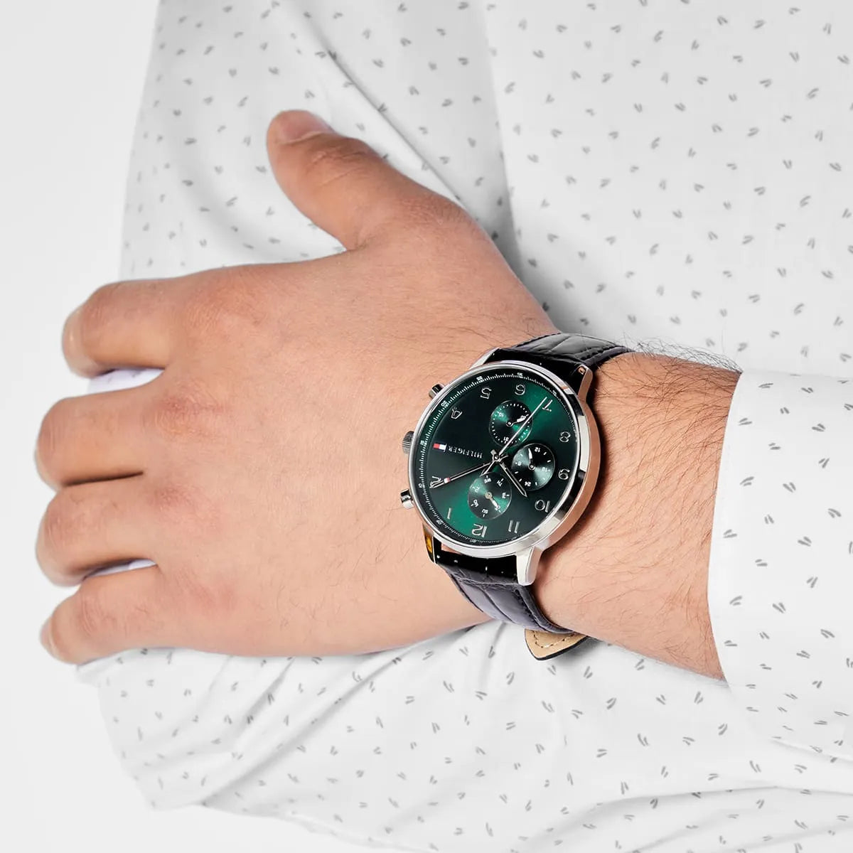 Tommy Hilfiger green dial watch worn on male wrist, showing chronograph design and silver case