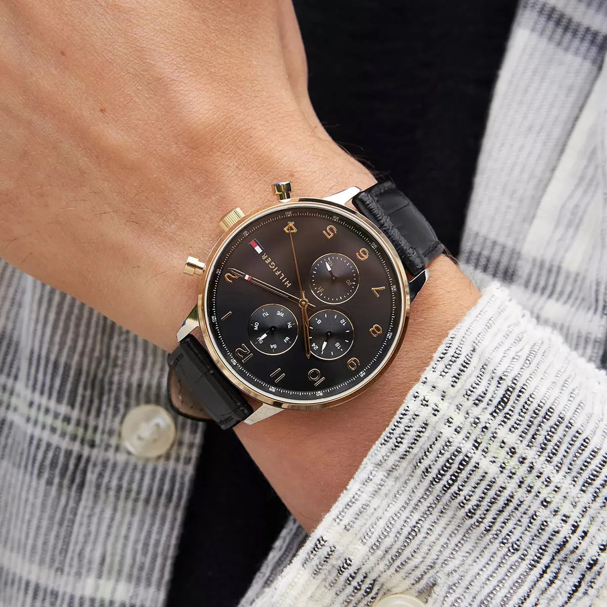 Tommy Hilfiger Leonard watch on wrist with striped shirt, displaying dial and strap details