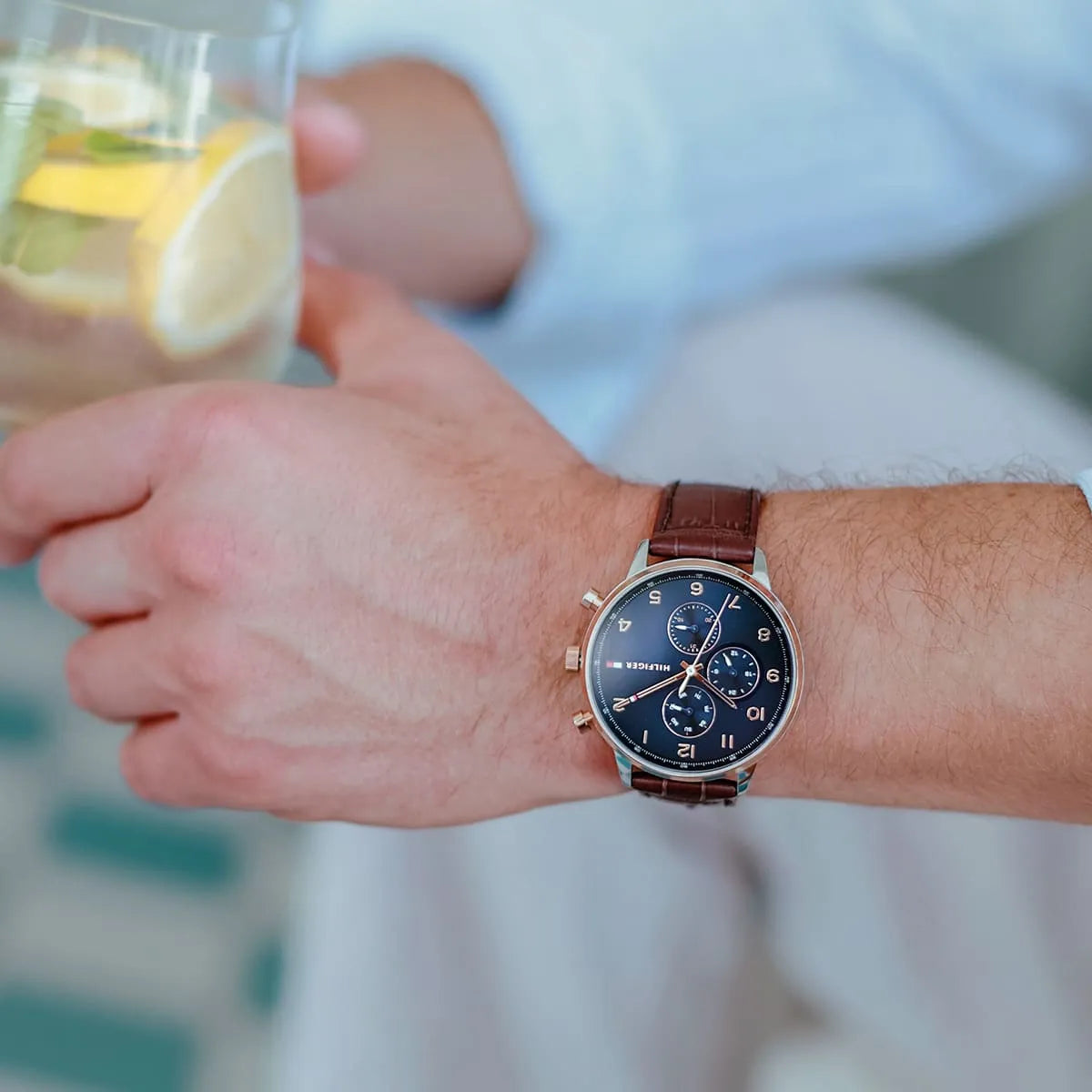 Tommy Hilfiger Leonard chronograph watch worn on wrist by man holding glass