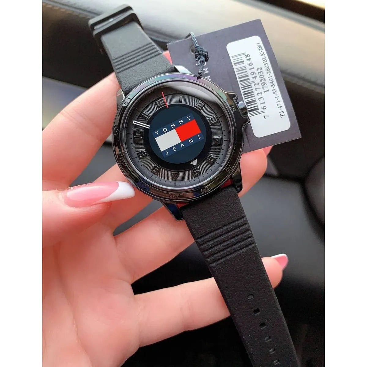 Tommy Hilfiger Jeans watch held in hand showing black dial and strap detail