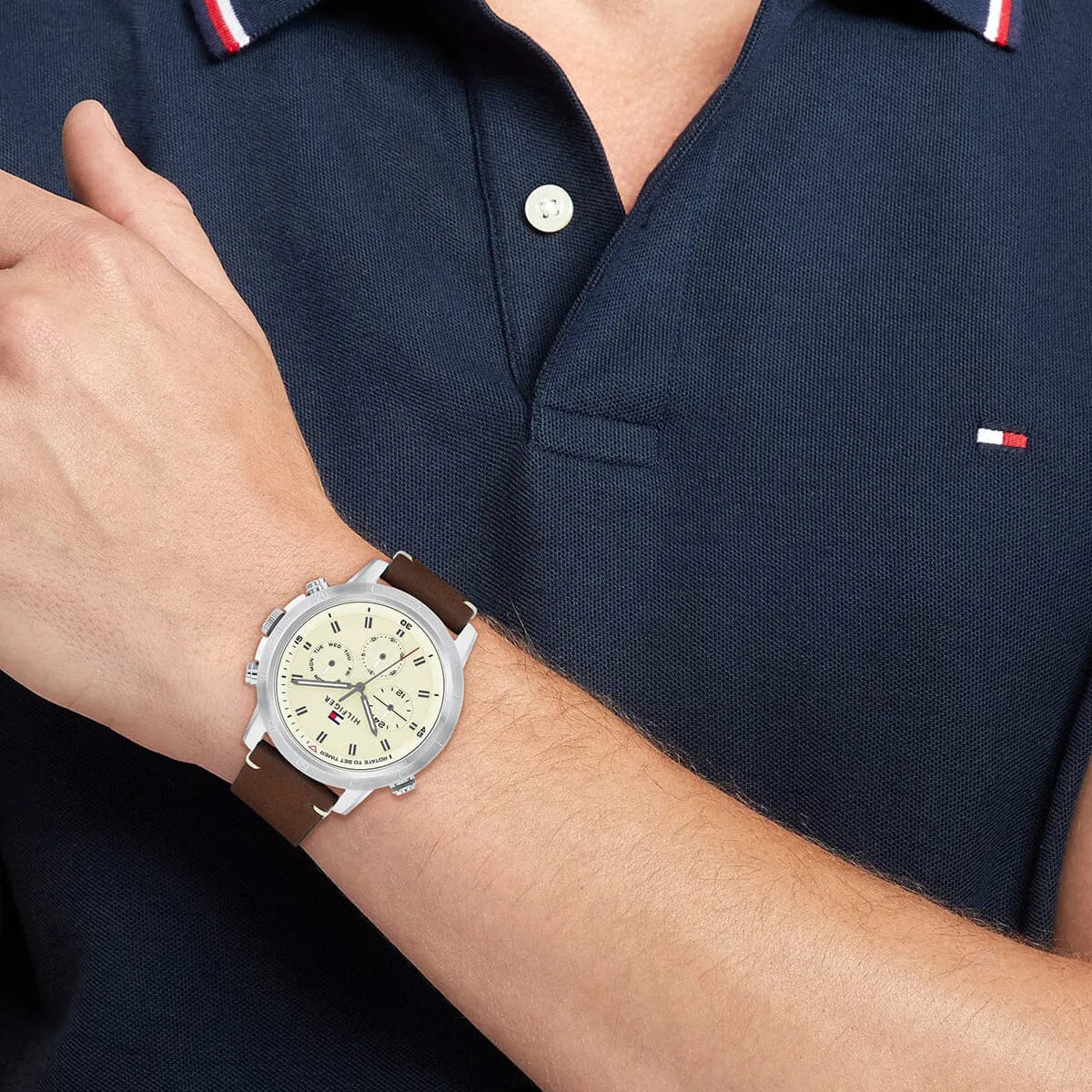Tommy Hilfiger Troy watch on wrist, lifestyle shot with navy polo shirt