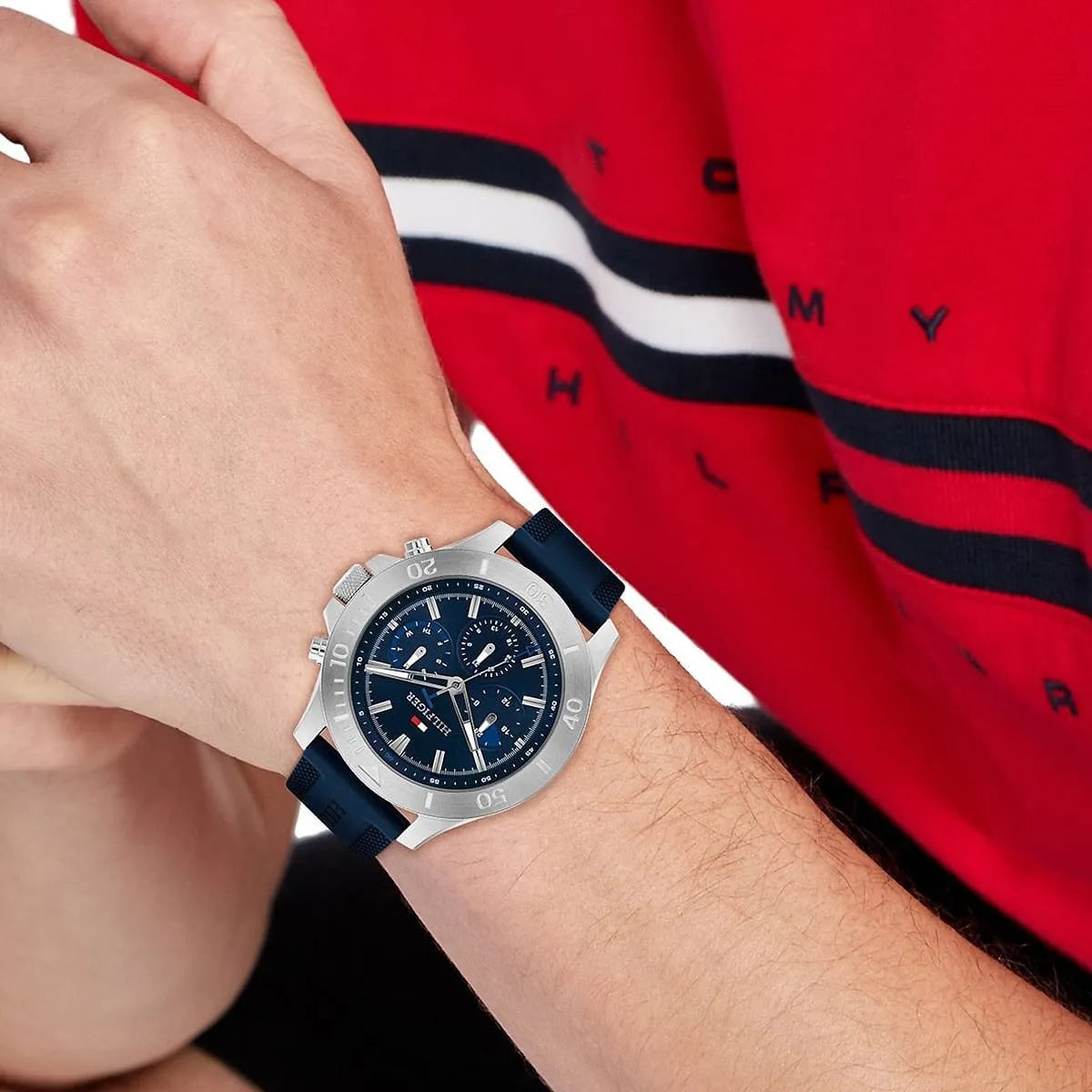 Tommy Hilfiger blue chronograph watch worn on wrist with red striped shirt