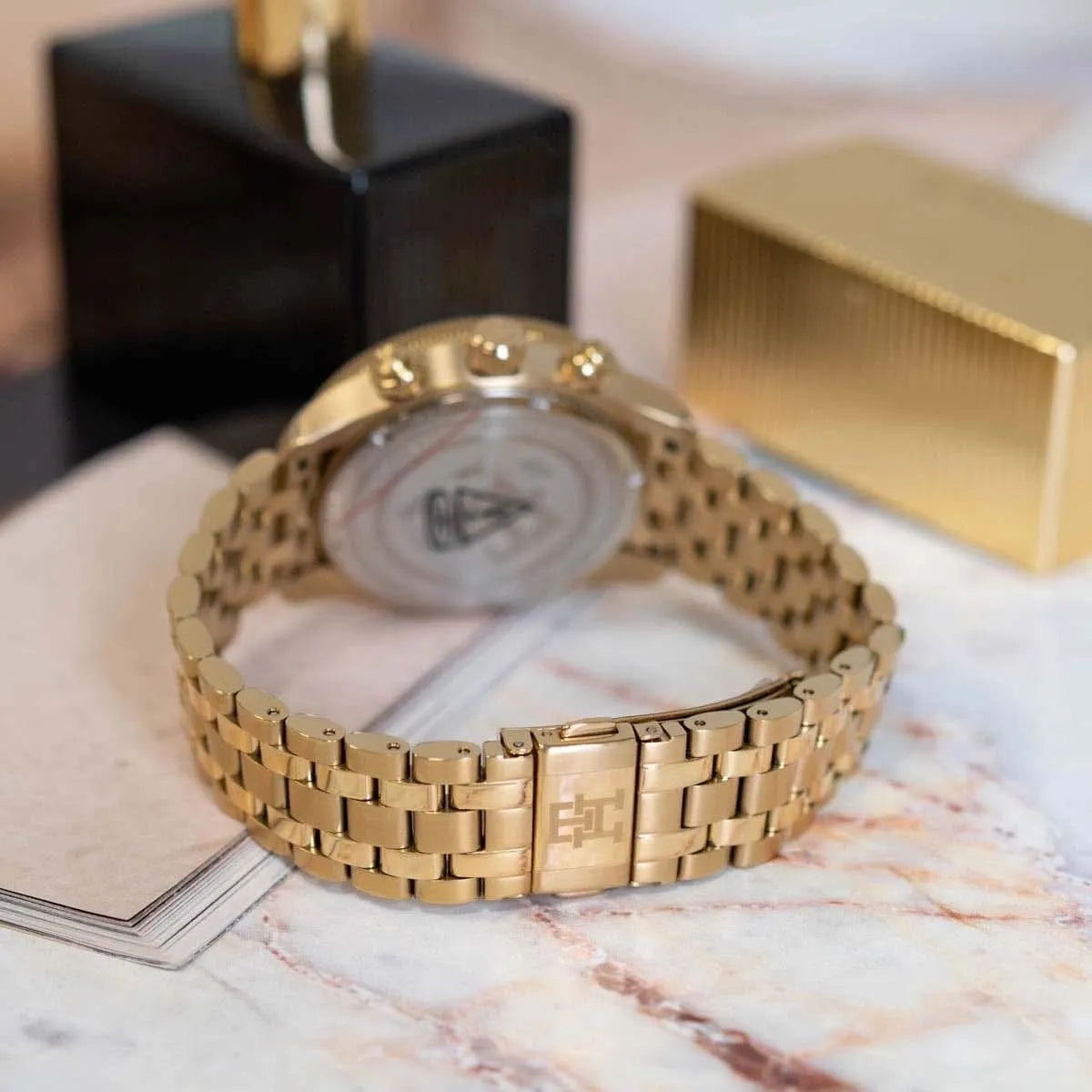 Tommy Hilfiger gold chronograph watch displayed on table next to branded box