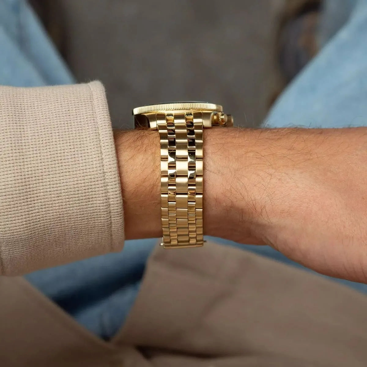 Gold stainless steel chronograph watch worn on wrist highlighting bracelet design detail