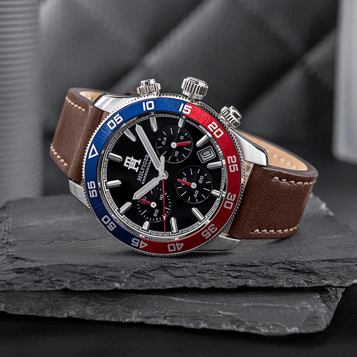 TH85 chronograph on textured surface showing blue and red bezel with dial