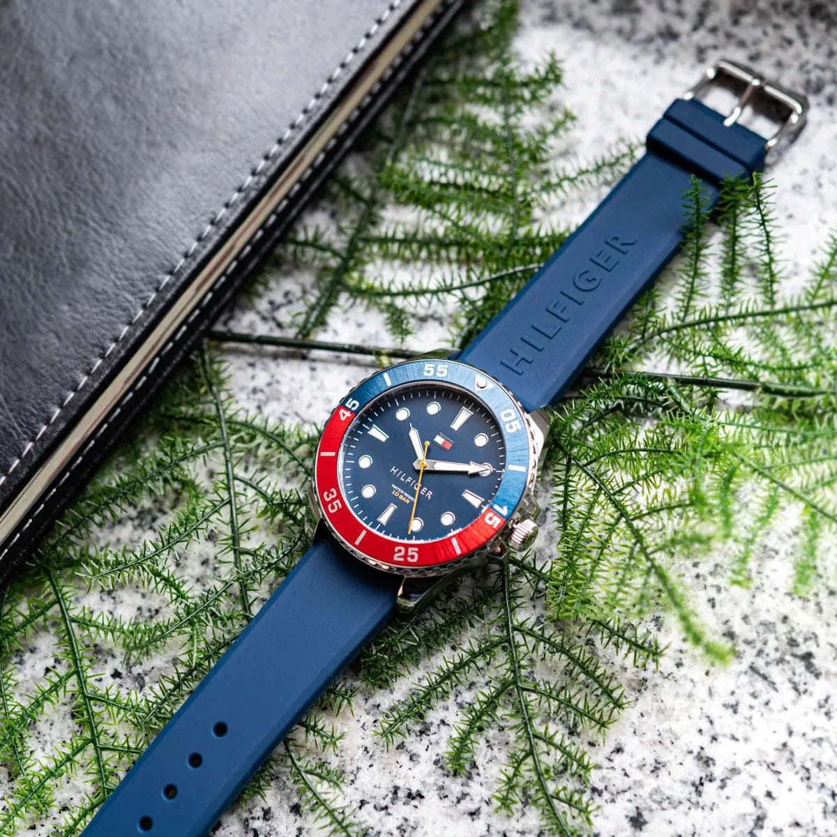 Navy silicone strap of Tommy Hilfiger watch with embossed 'HILFIGER' text and buckle closure