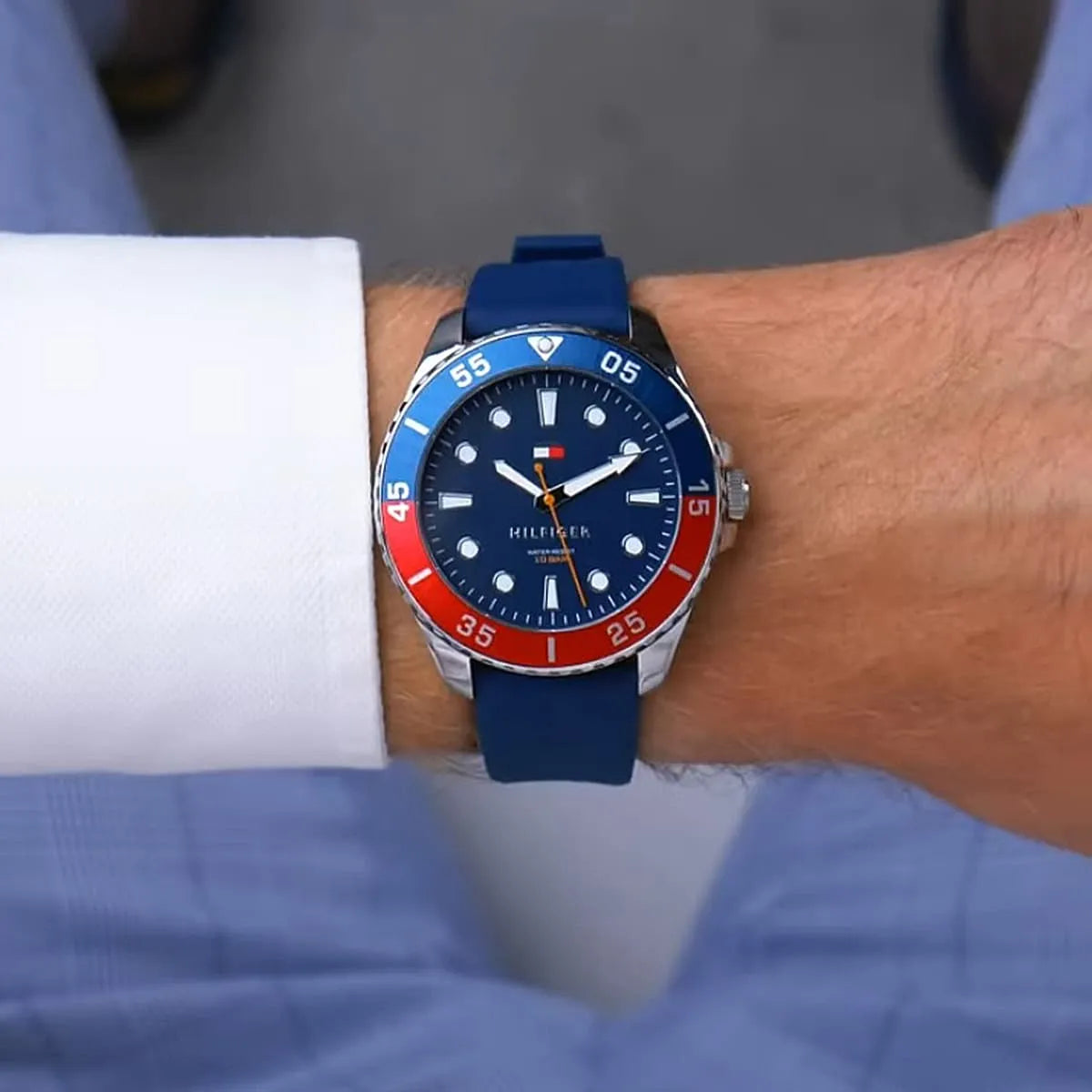 Tommy Hilfiger watch worn on wrist with navy dial, red bezel section, white hour markers, and silicone strap
