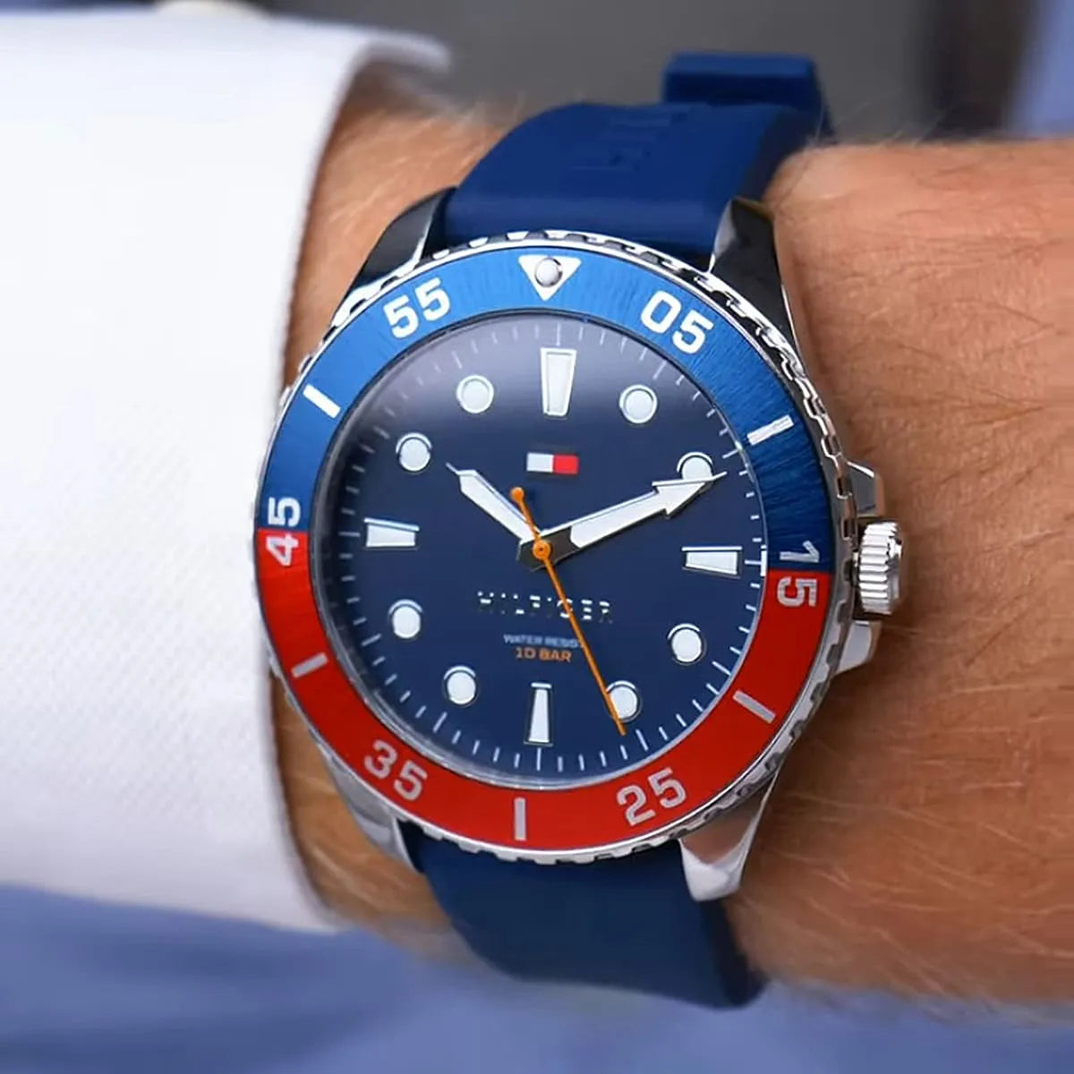Tommy Hilfiger men's watch on wrist showing blue dial, red/blue rotating bezel, and navy silicone band