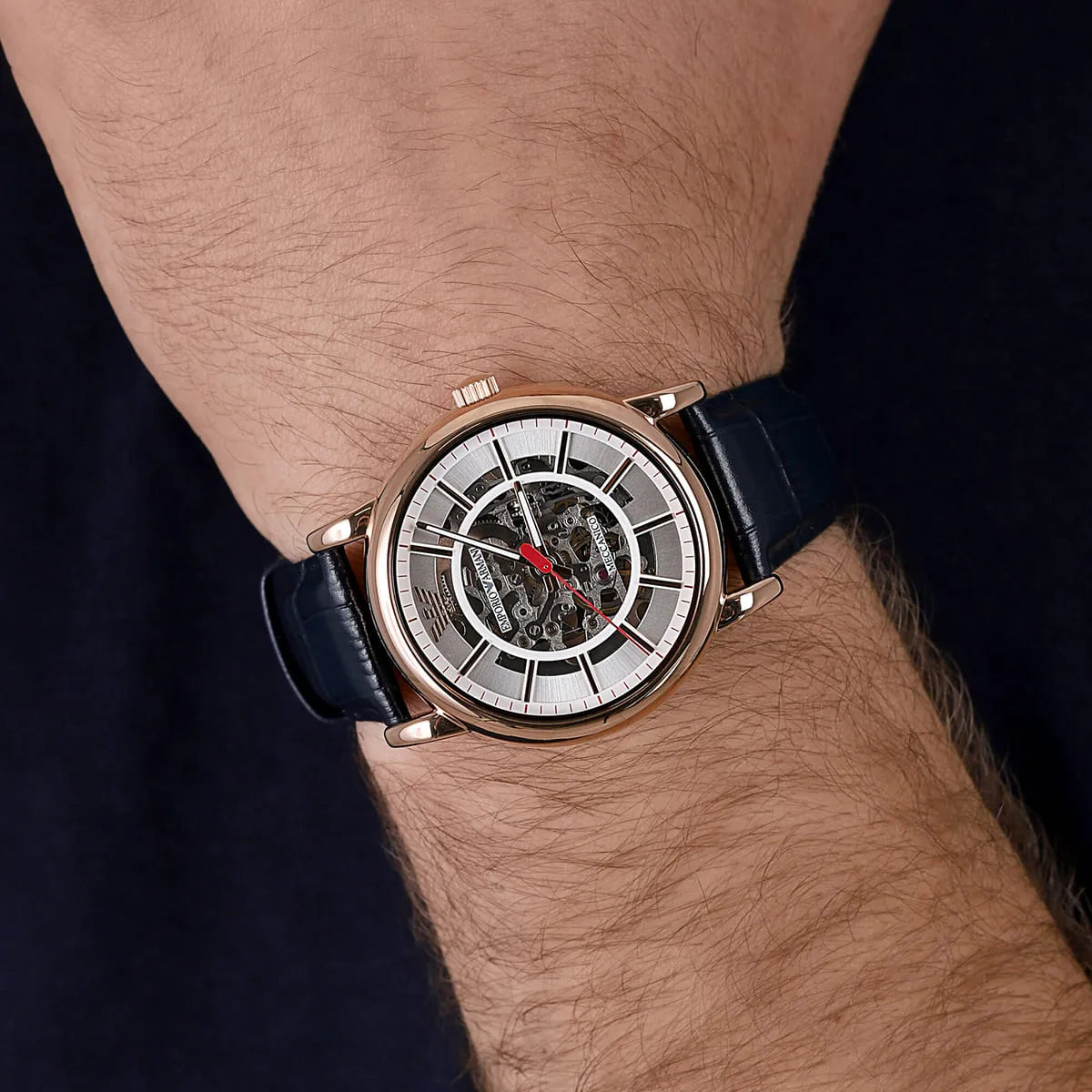 Emporio Armani AR60009 automatic skeleton watch on wrist showing white dial and navy leather strap