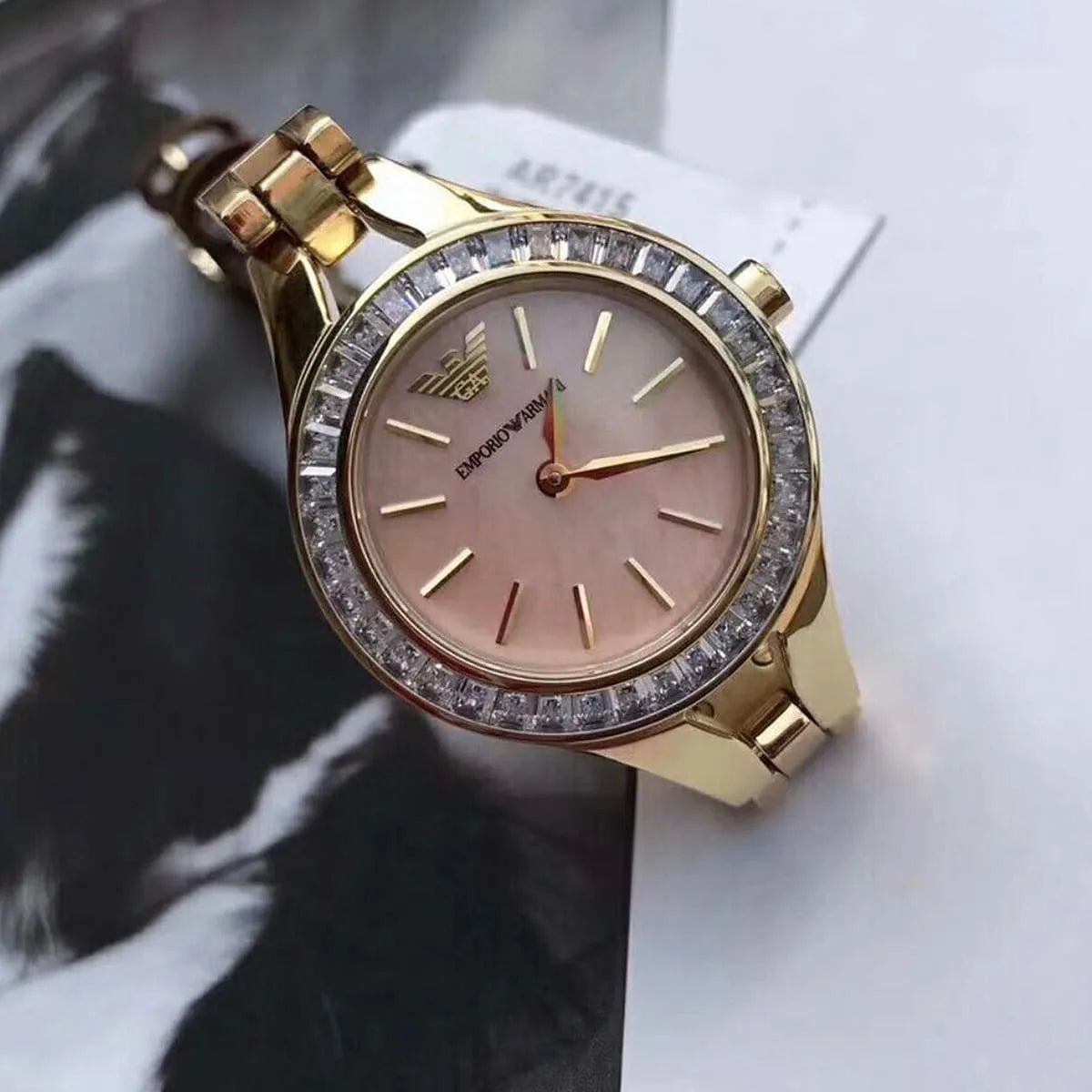 Close-up of Emporio Armani Chiara dial showing pink face with crystal bezel and gold hands