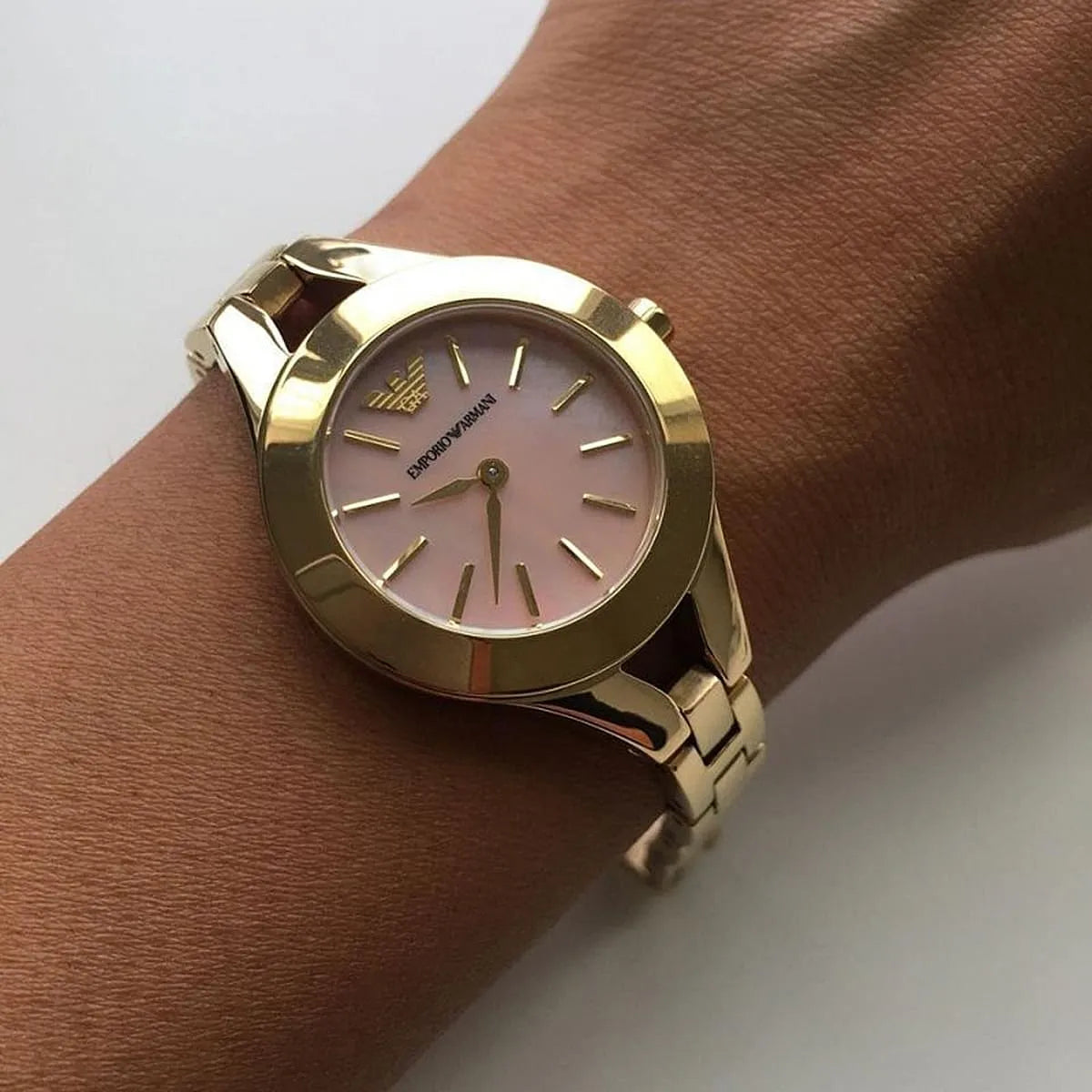 Emporio Armani Chiara watch with pink dial worn on wrist showing gold bracelet