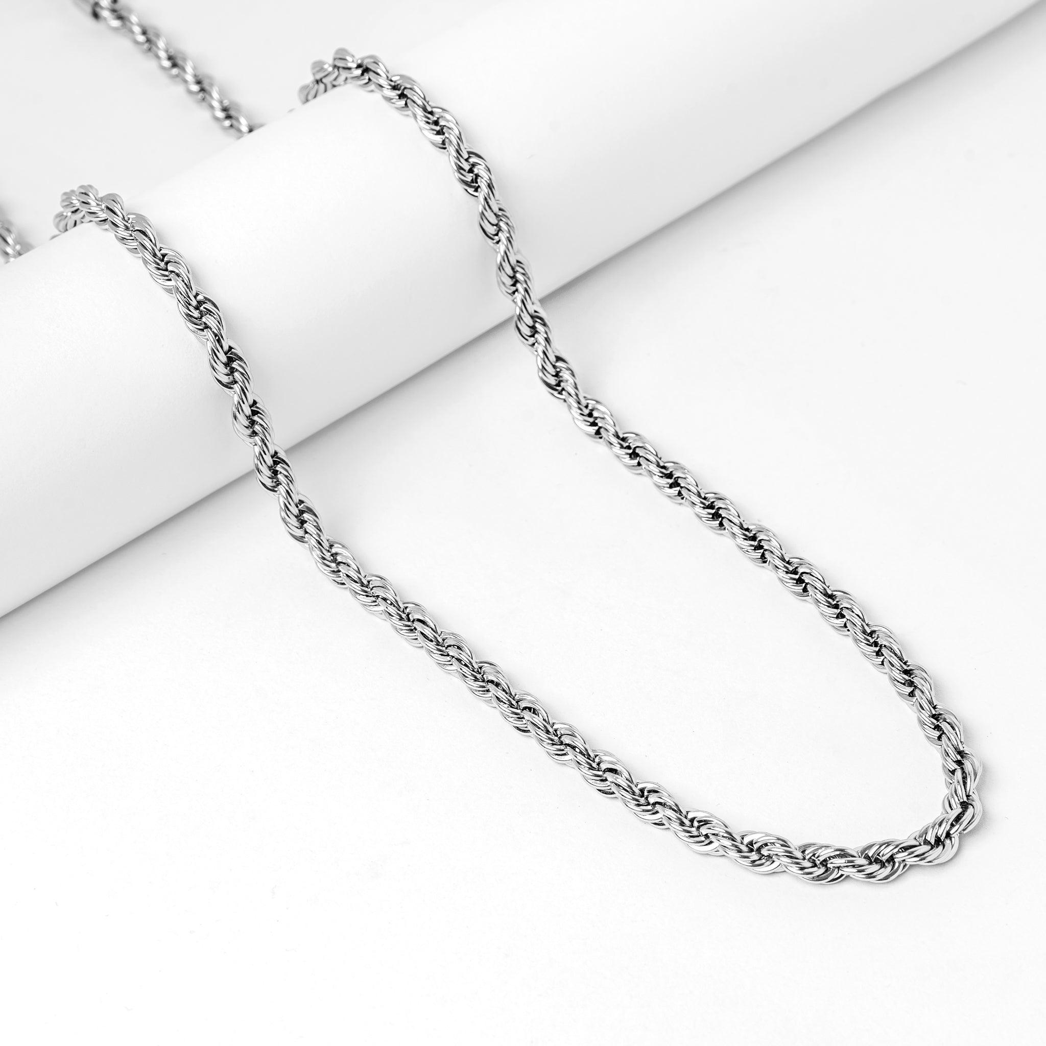 Silver rope chain necklace styled on white decorative block