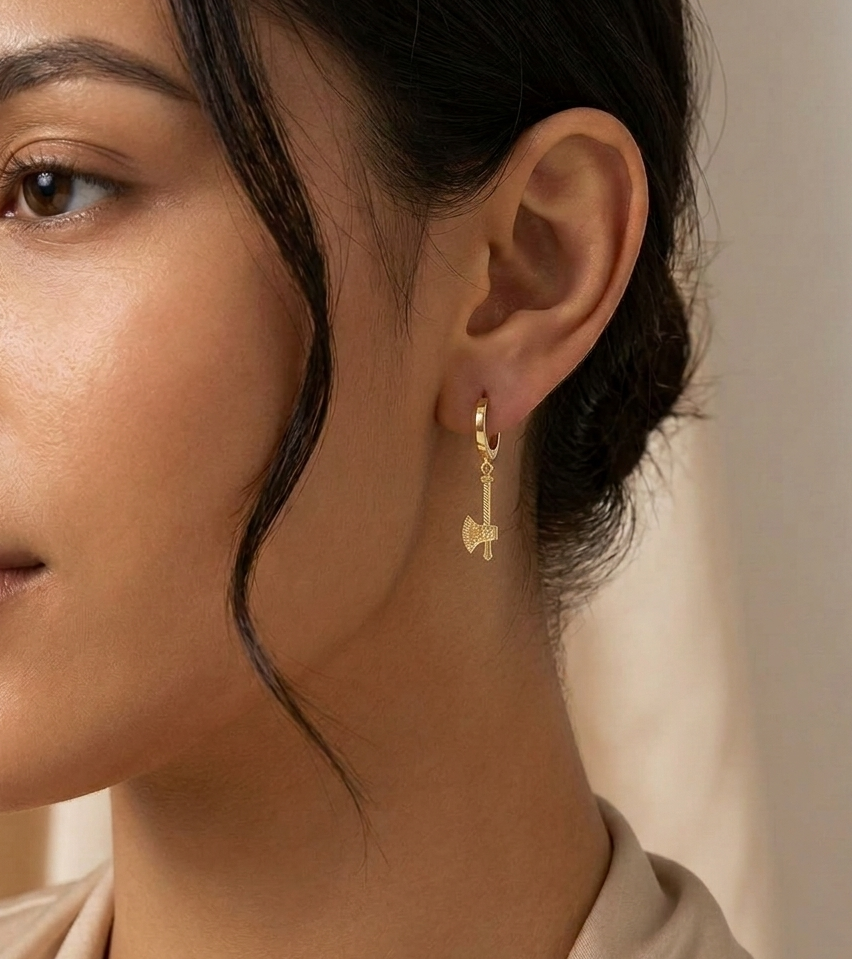 Gold axe drop earring worn on person