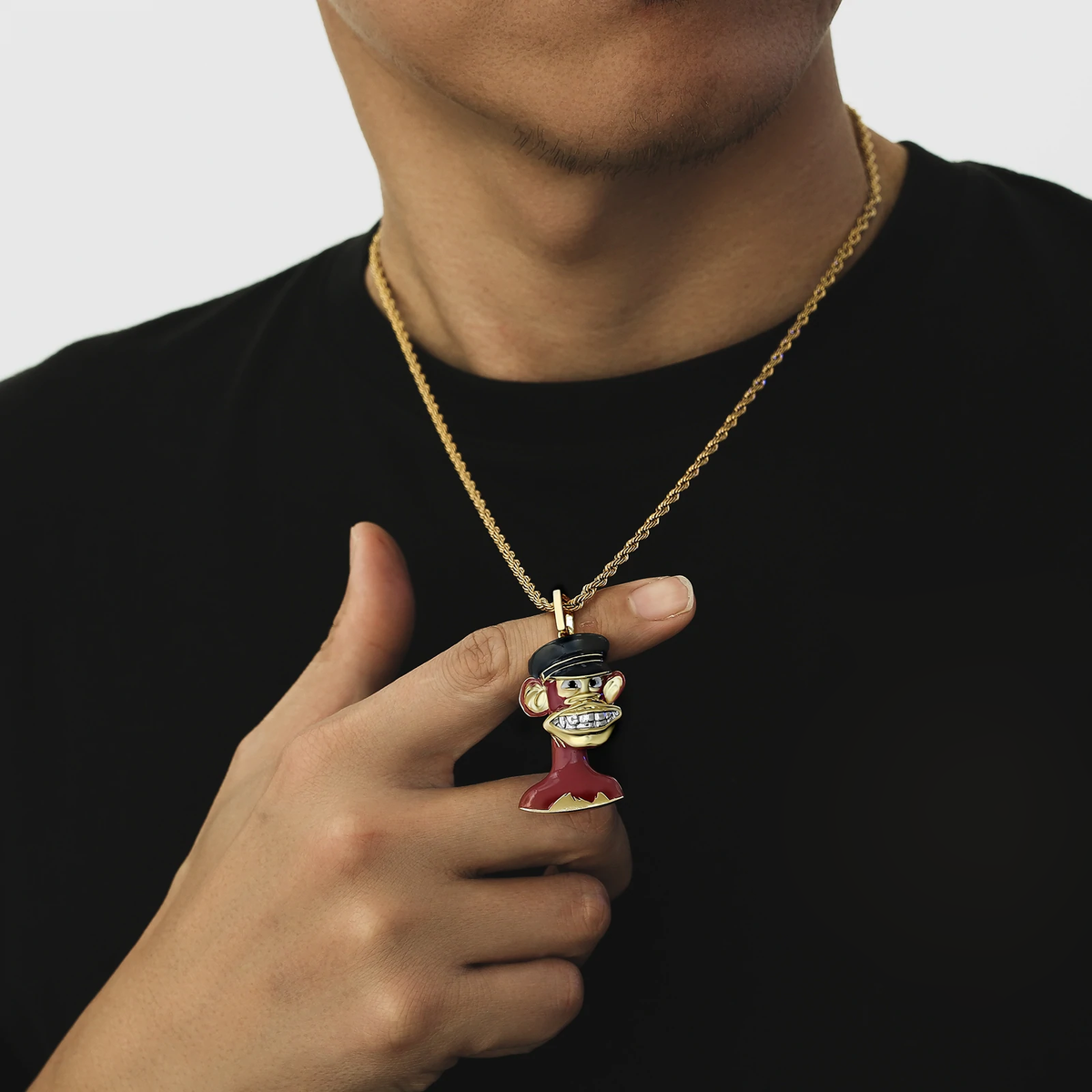 Close-up of Big Daddy Bored Ape NFT pendant #6 held in hand, showing gold and red enamel details