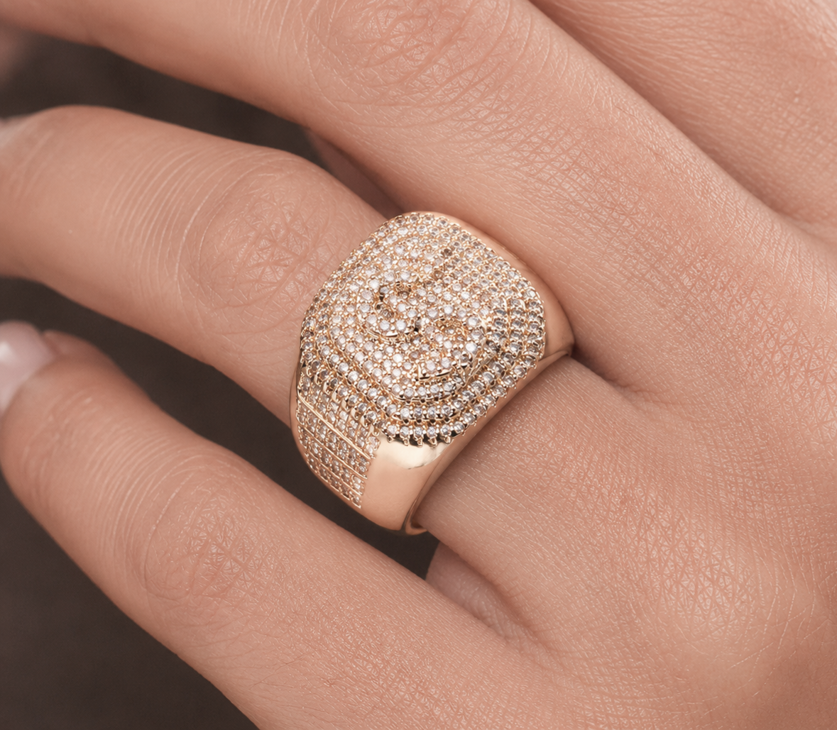 Dollar sign iced out ring worn on hand showing crystal-covered dome design