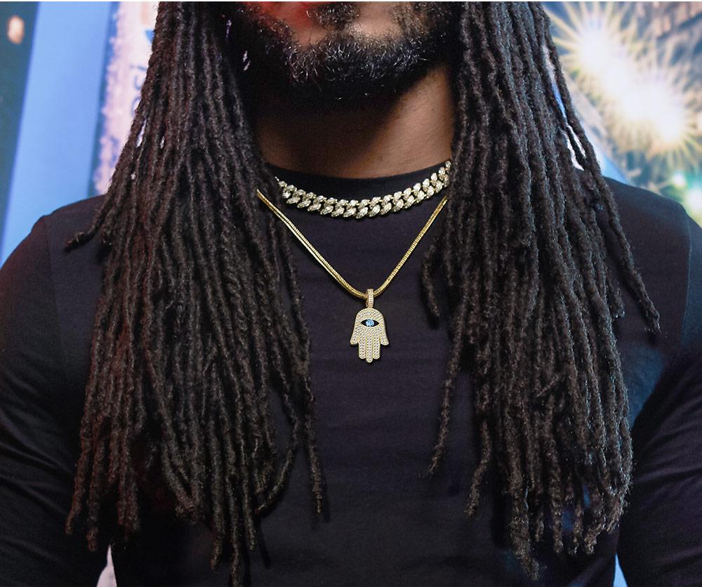 Hamsa hand pendant necklace worn on person with dreadlocks and black shirt