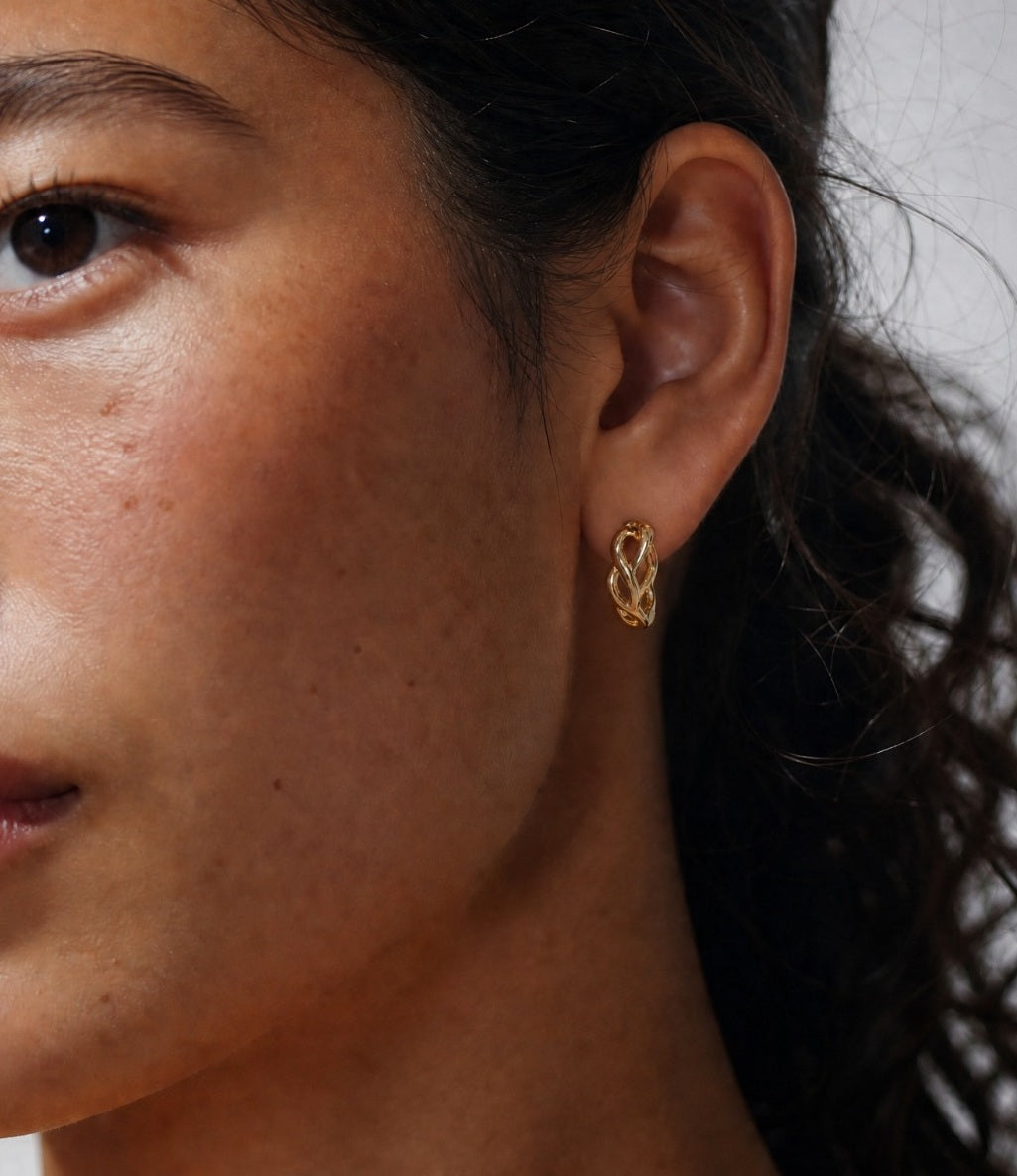 Woman wearing Big Daddy intertwined hollow gold hoop earring on ear