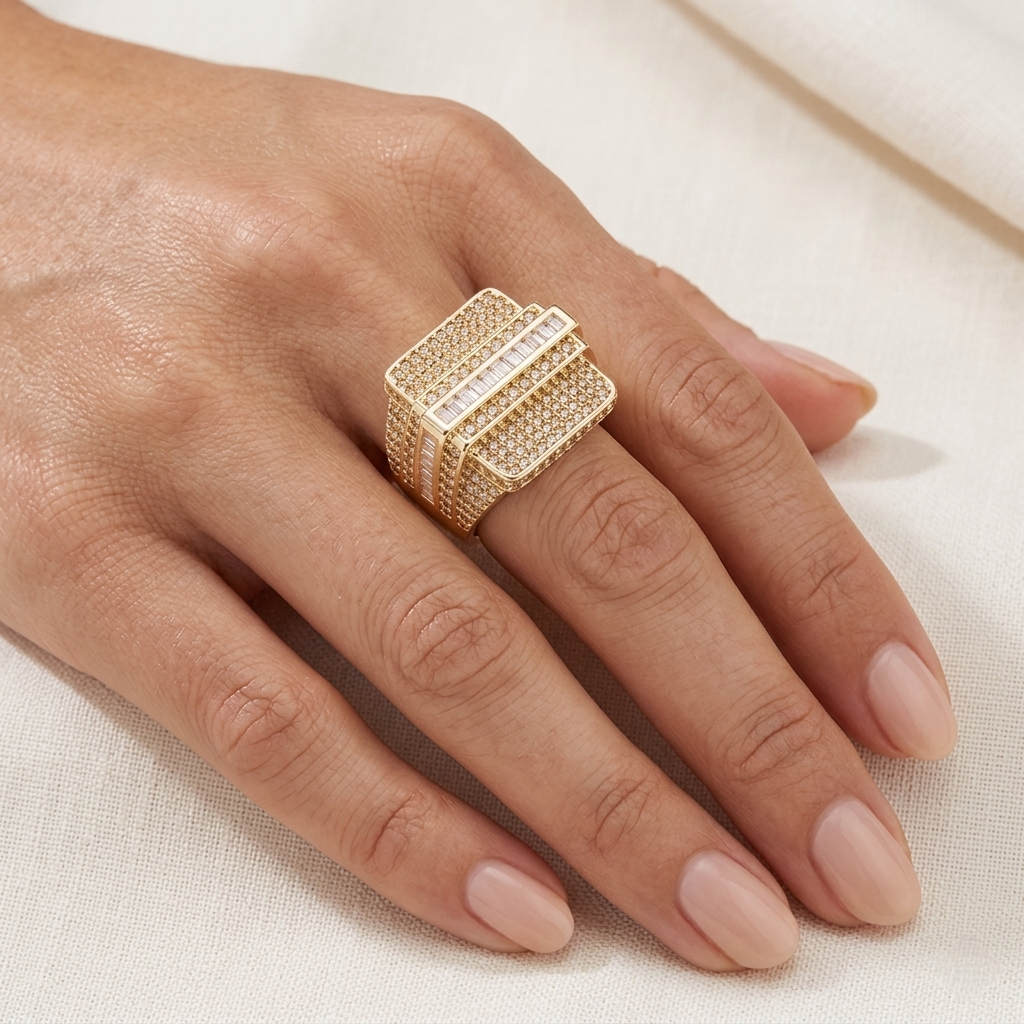 Gold iced out baguette diamond ring worn on hand against white background