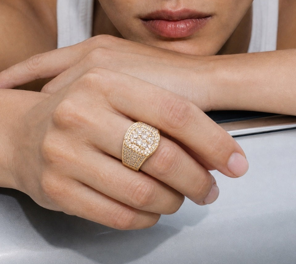 Gold iced out ring worn on hand displaying cushion stone setting