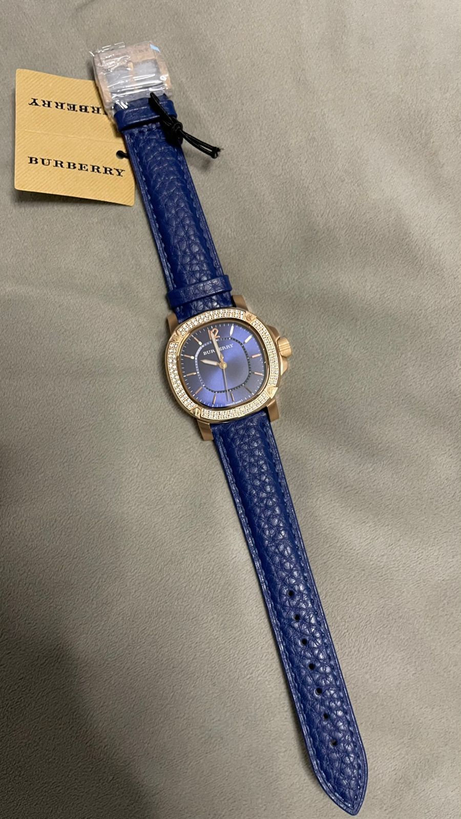 Burberry rose gold ladies watch with navy strap on wrist with packaging tag